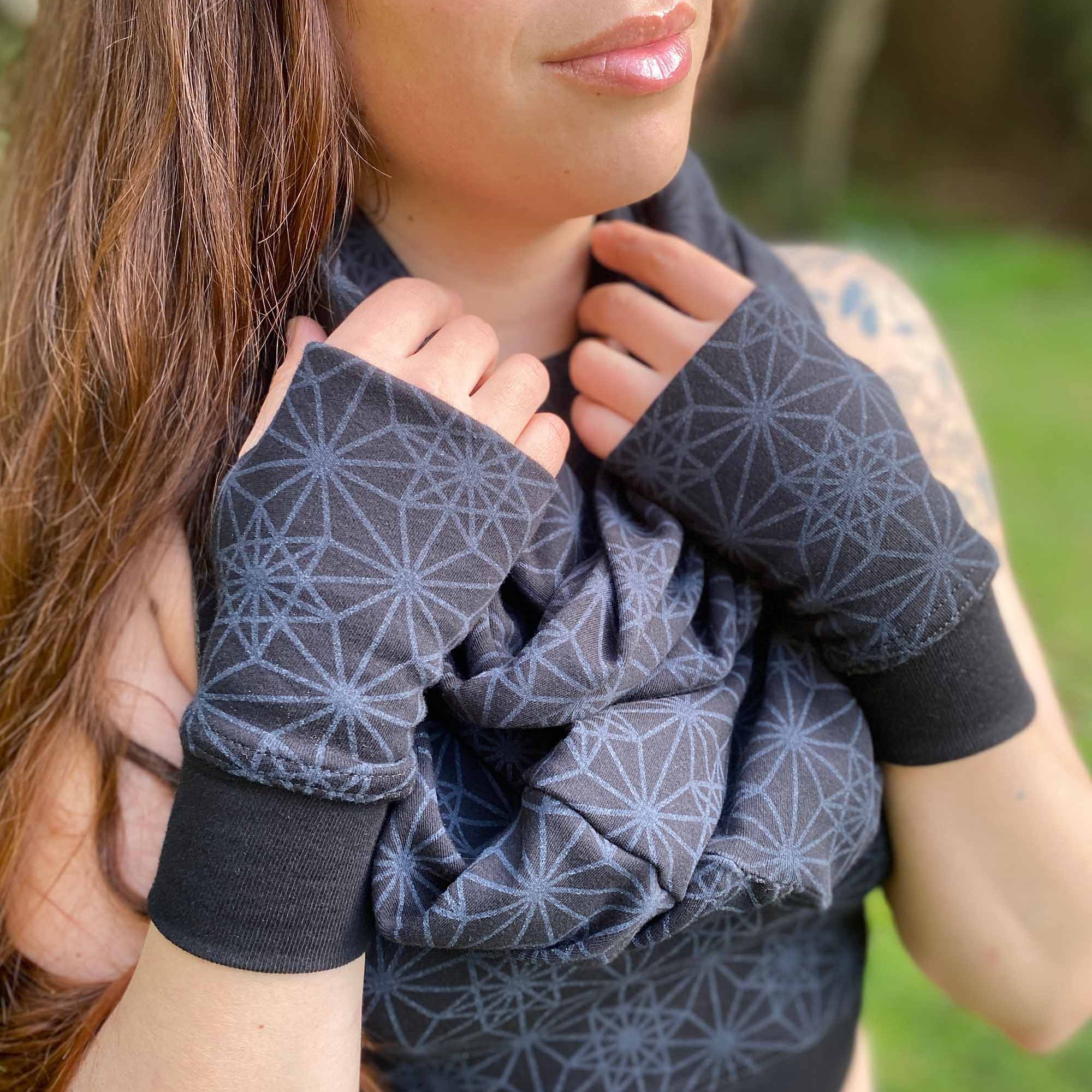 Organic cotton hand warmers and matching scarf in black fabric and geometric print, right side view on female model.