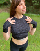 Organic cotton crop top and matching hand warmers in black fabric and geometric print, worn by female.