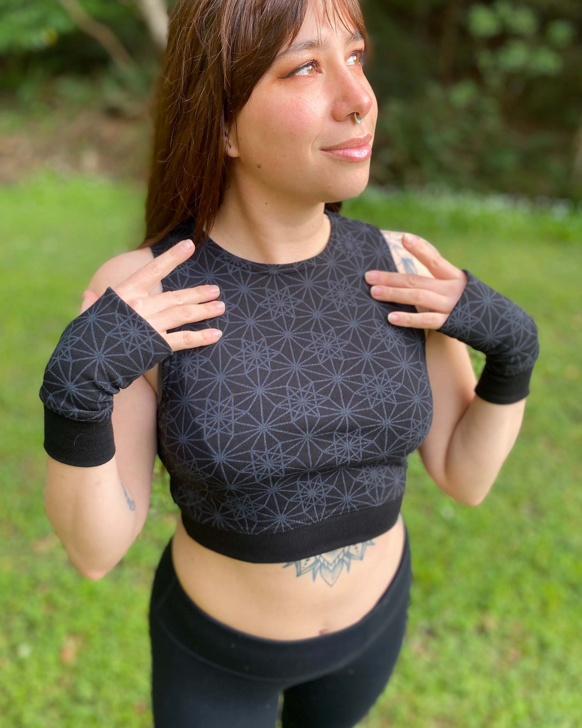 Organic cotton crop top and matching hand warmers in black fabric and geometric print, worn by female.