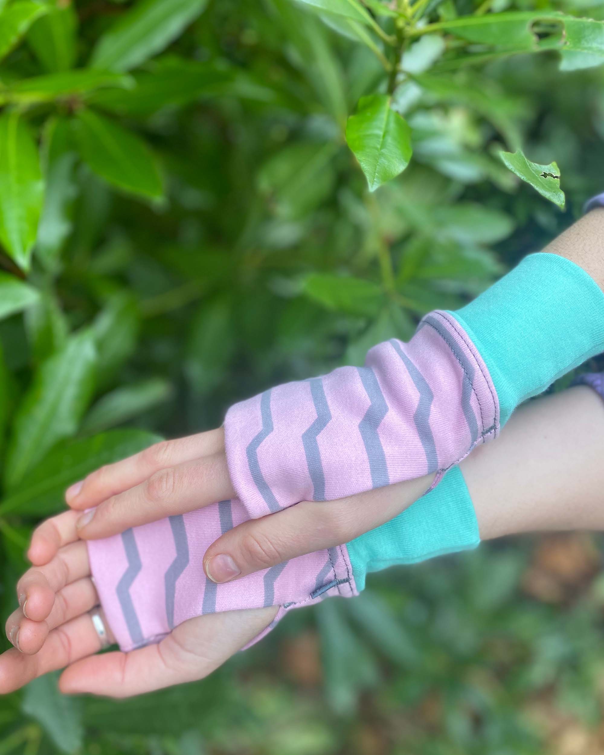 Organic cotton fingerless gloves in pink fabric with geometric print, under side view.