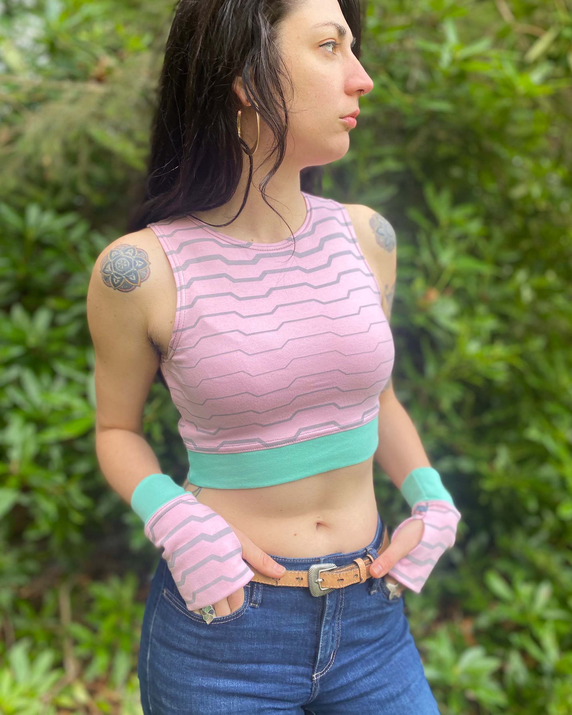Organic cotton fingerless gloves and crop top in pink fabric with geometric print, on female model.