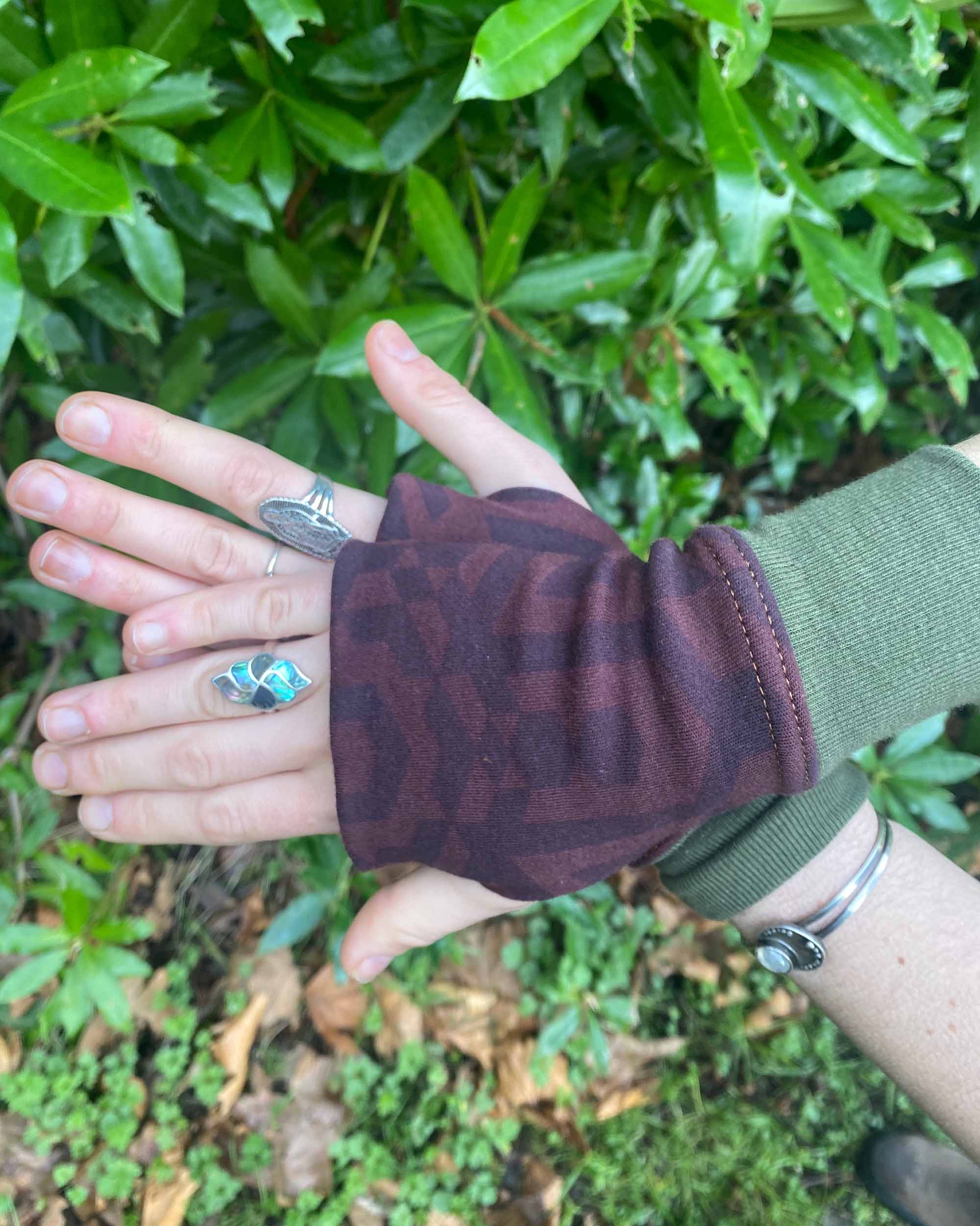 Organic cotton fingerless gloves in reddish brown colored fabric with geometric print, top view.