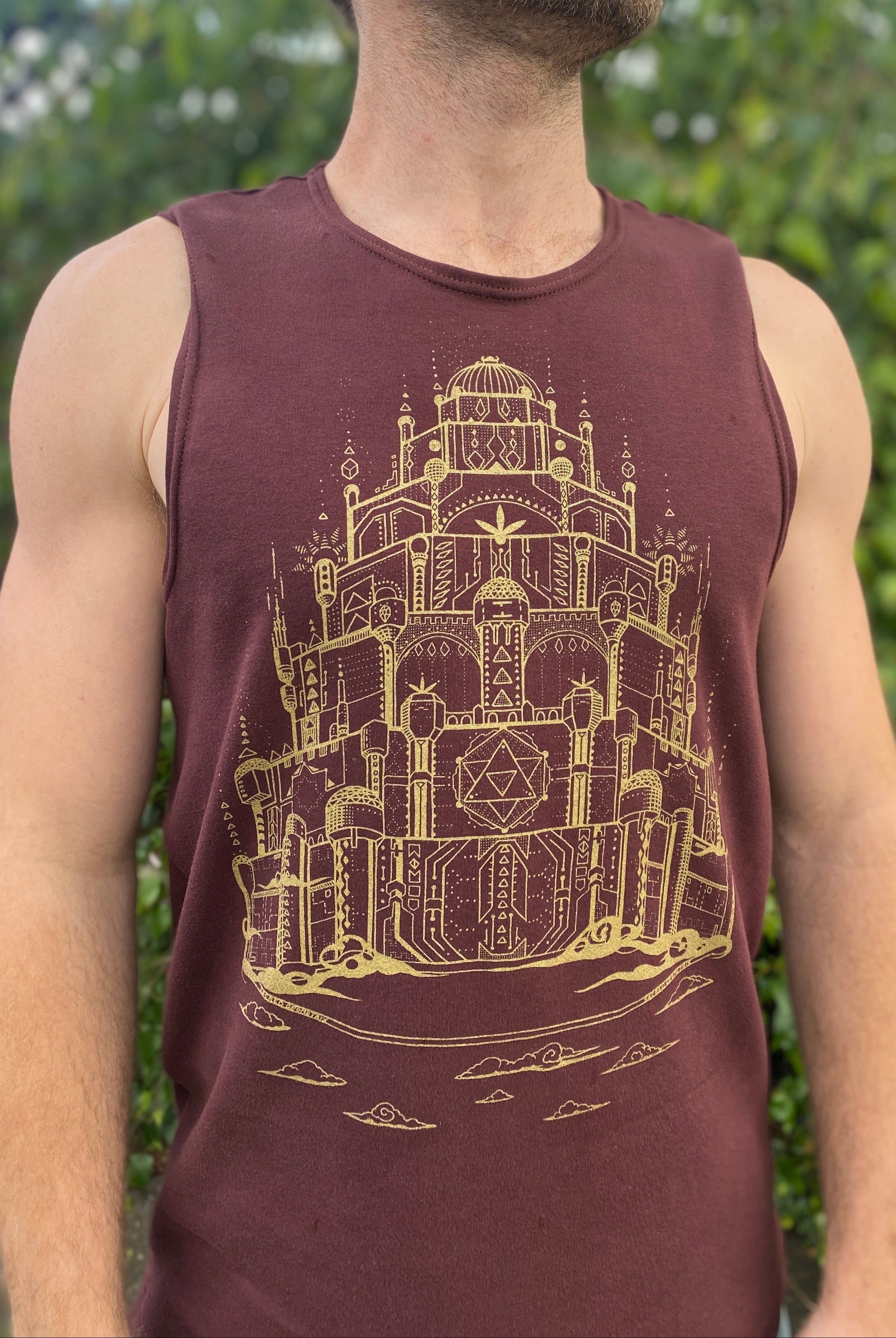 Man wearing a organic cotton brown tank top with a gold screen print design.