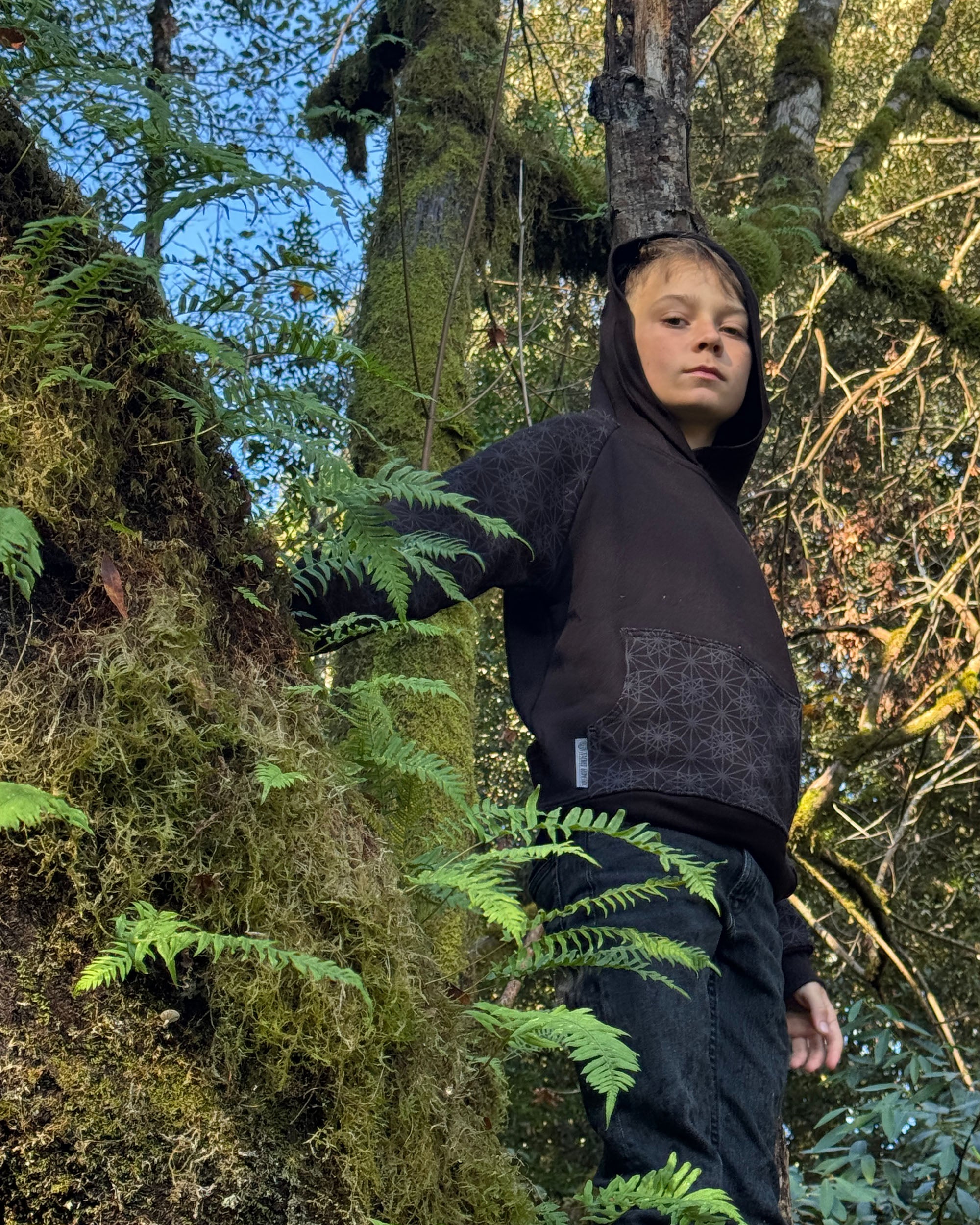 Organic cotton youth fleece hoodie, black with geometric printed sleeves, below view, boy model.