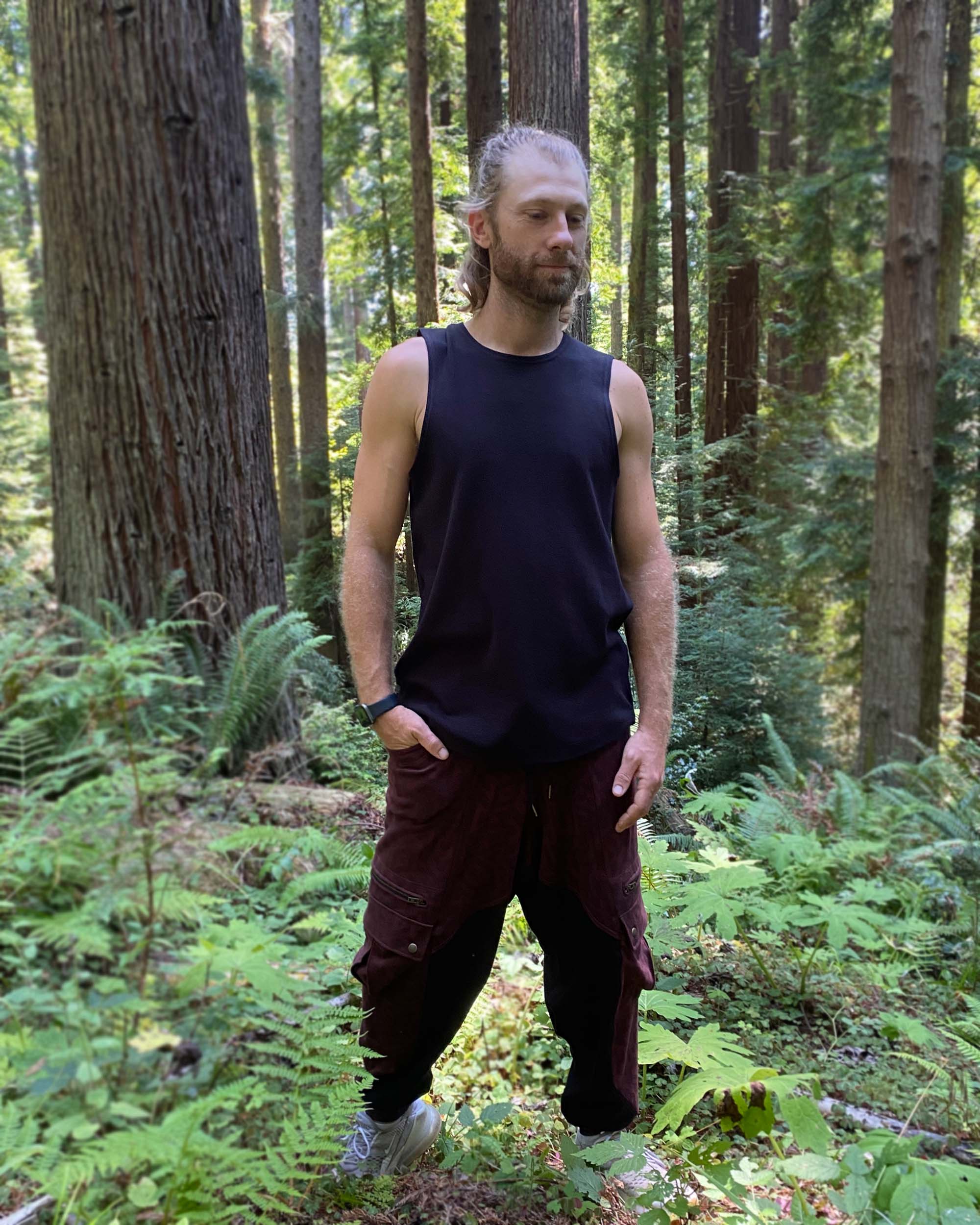 Organic cotton mens tank top, black fabric, front view on model in nature.
