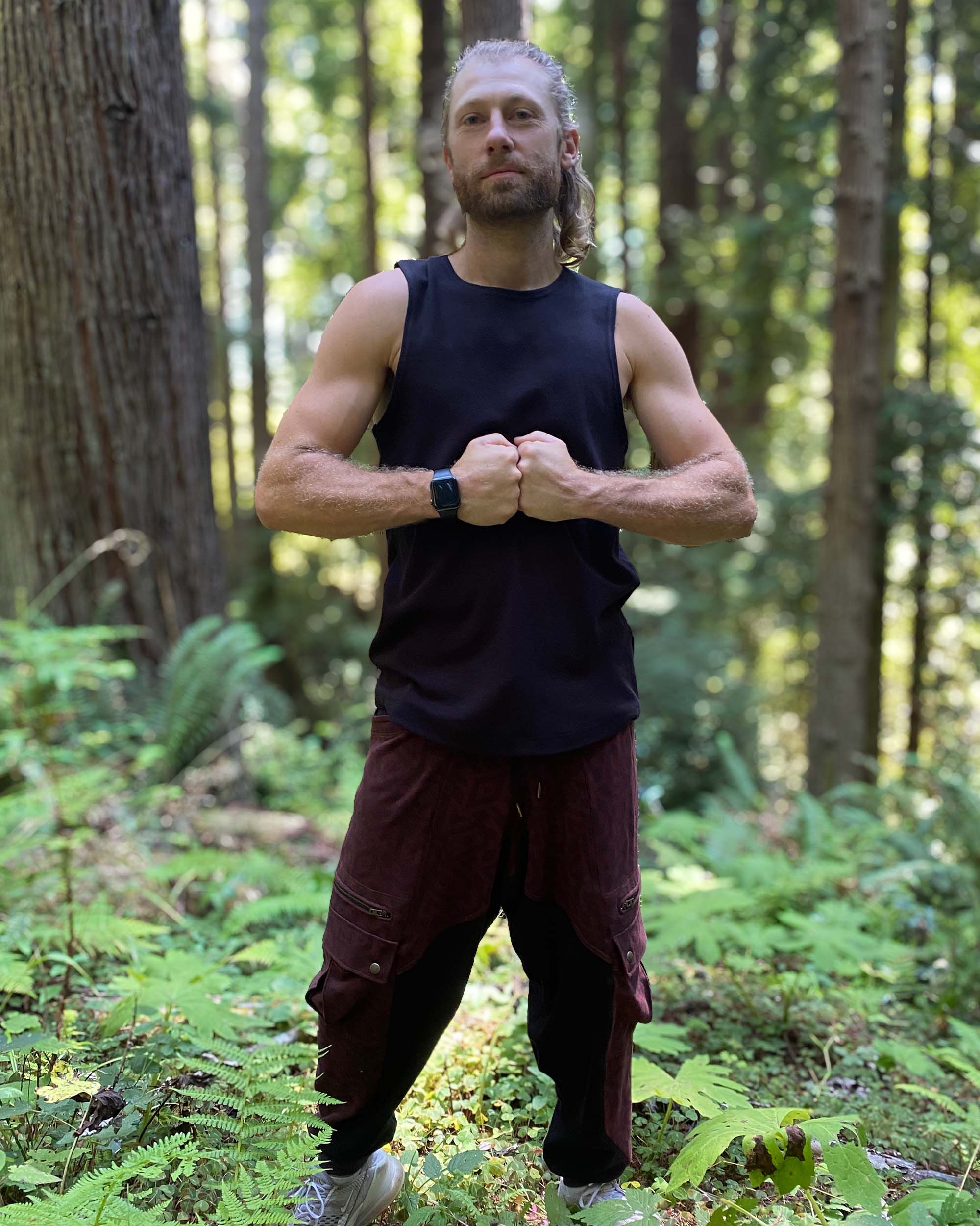 Organic cotton mens tank top, black fabric, front view on model flexing.