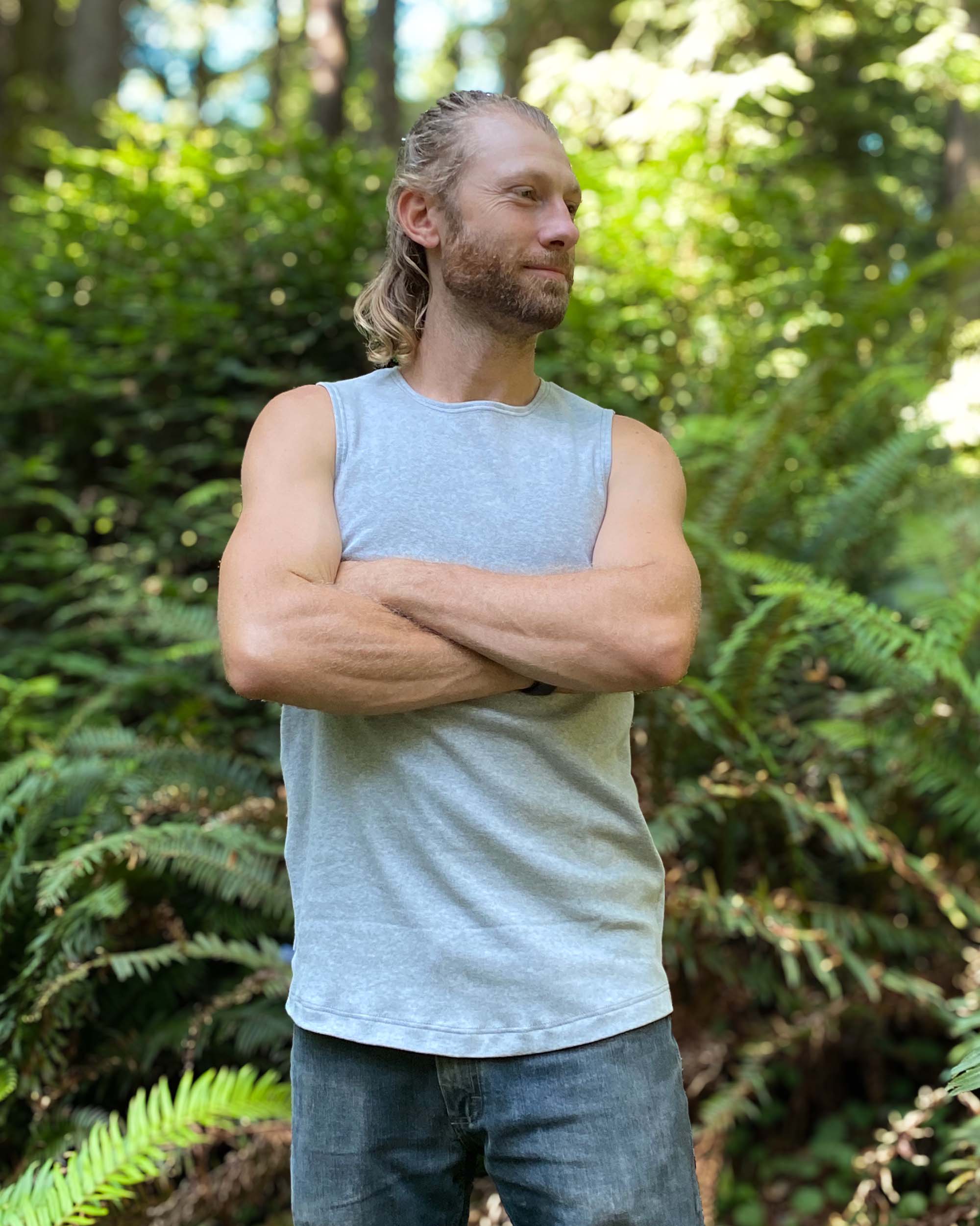 Organic cotton mens tank top, grey fabric, front view, on model with arms crossed.