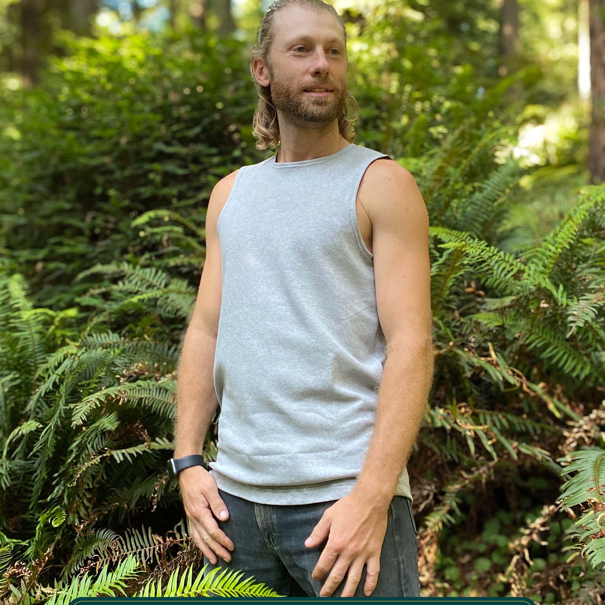 Organic cotton mens tank top, grey fabric, left side view, on model in nature.