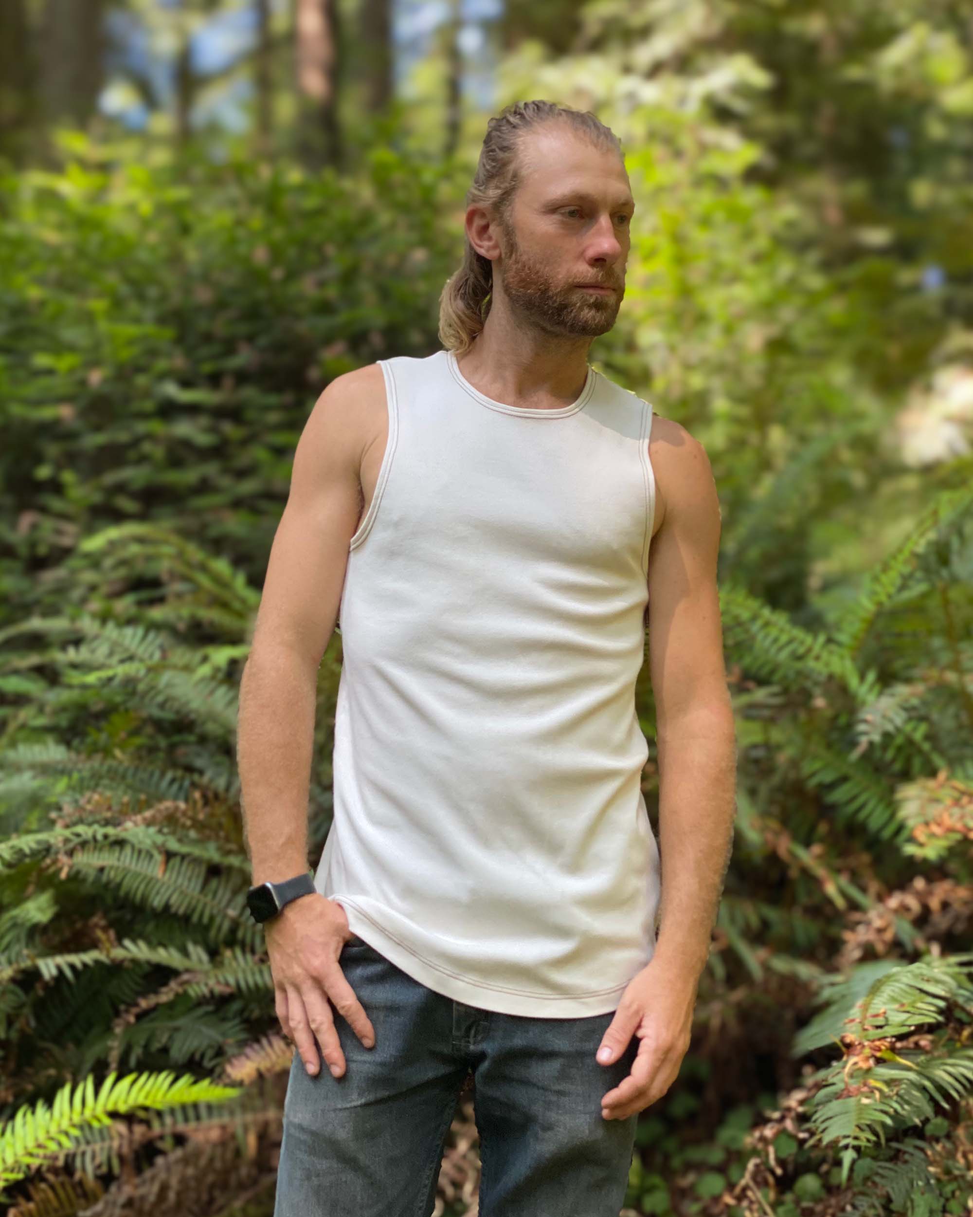 Organic cotton mens tank top, un-dyed fabric, front view, on model with ferns.