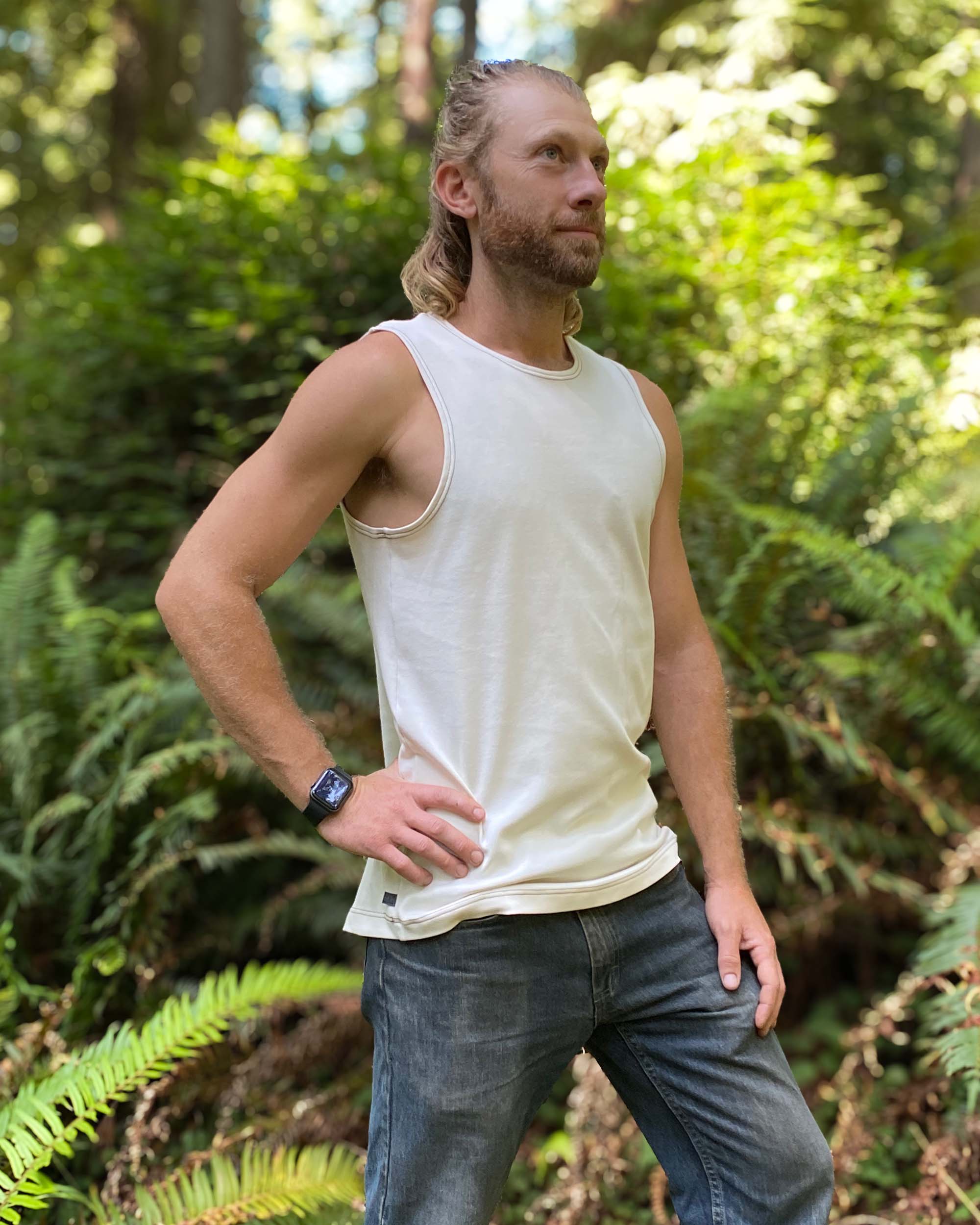 Organic cotton mens tank top, un-dyed fabric, right side view, on model in nature.