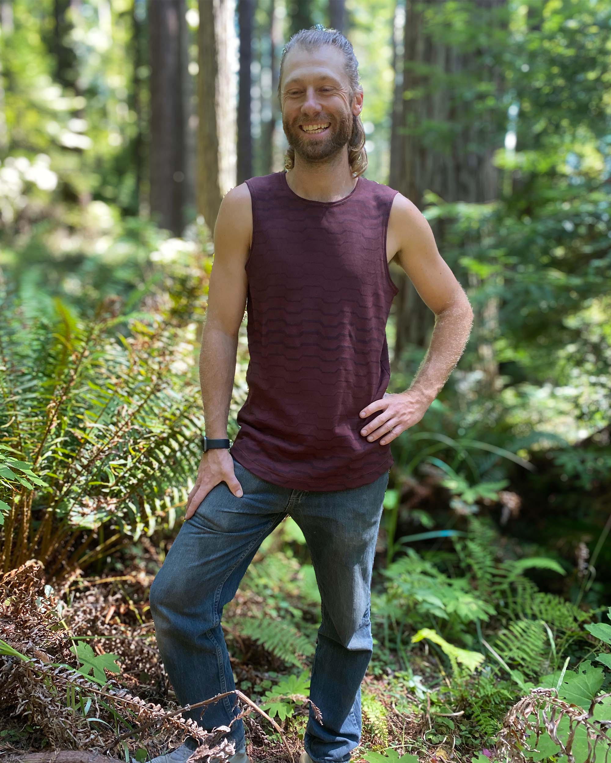 Organic cotton mens tank top, brown fabric with geometric print, front view in nature.