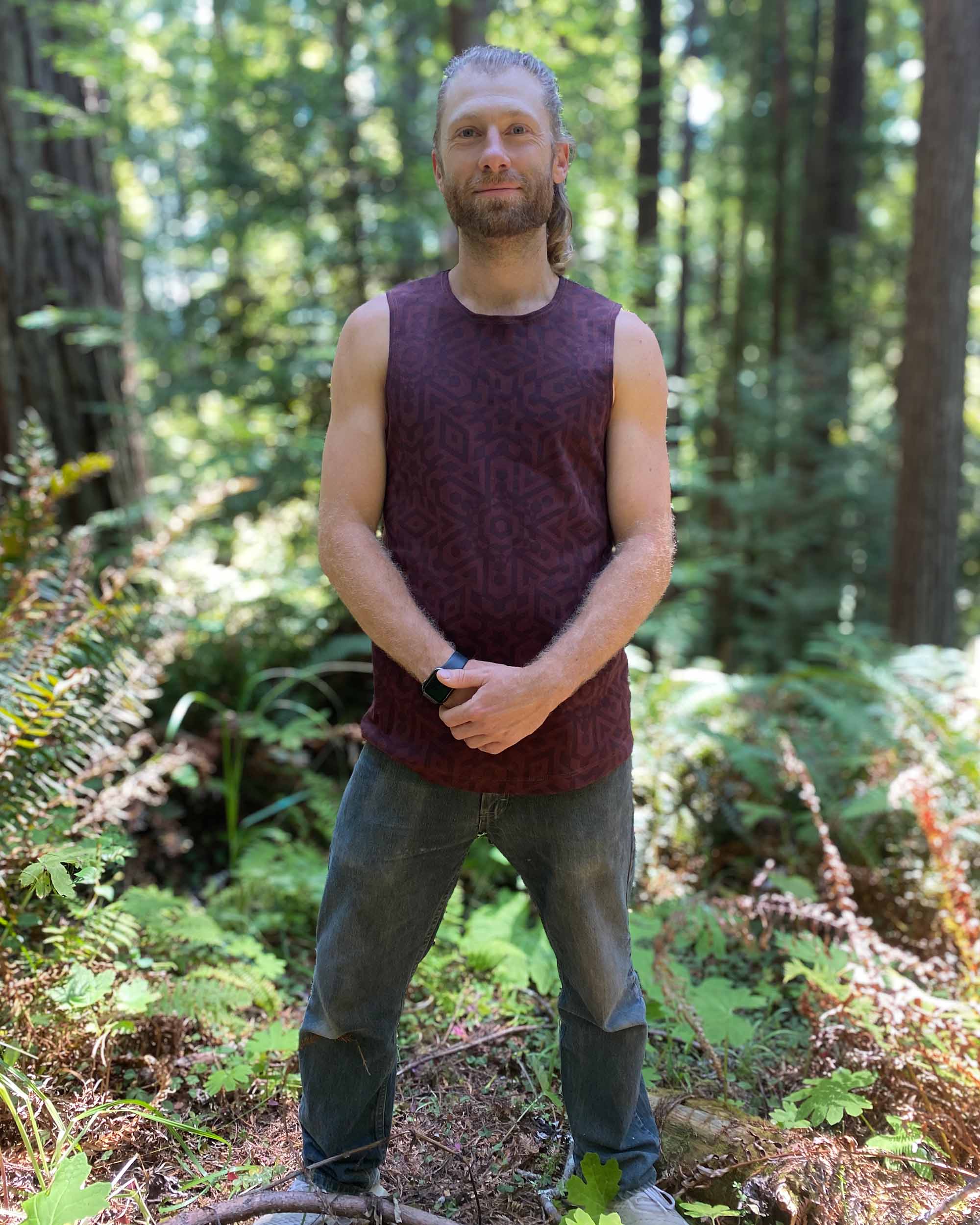 Organic cotton mens tank top, brown fabric with geometric print, front view on model.