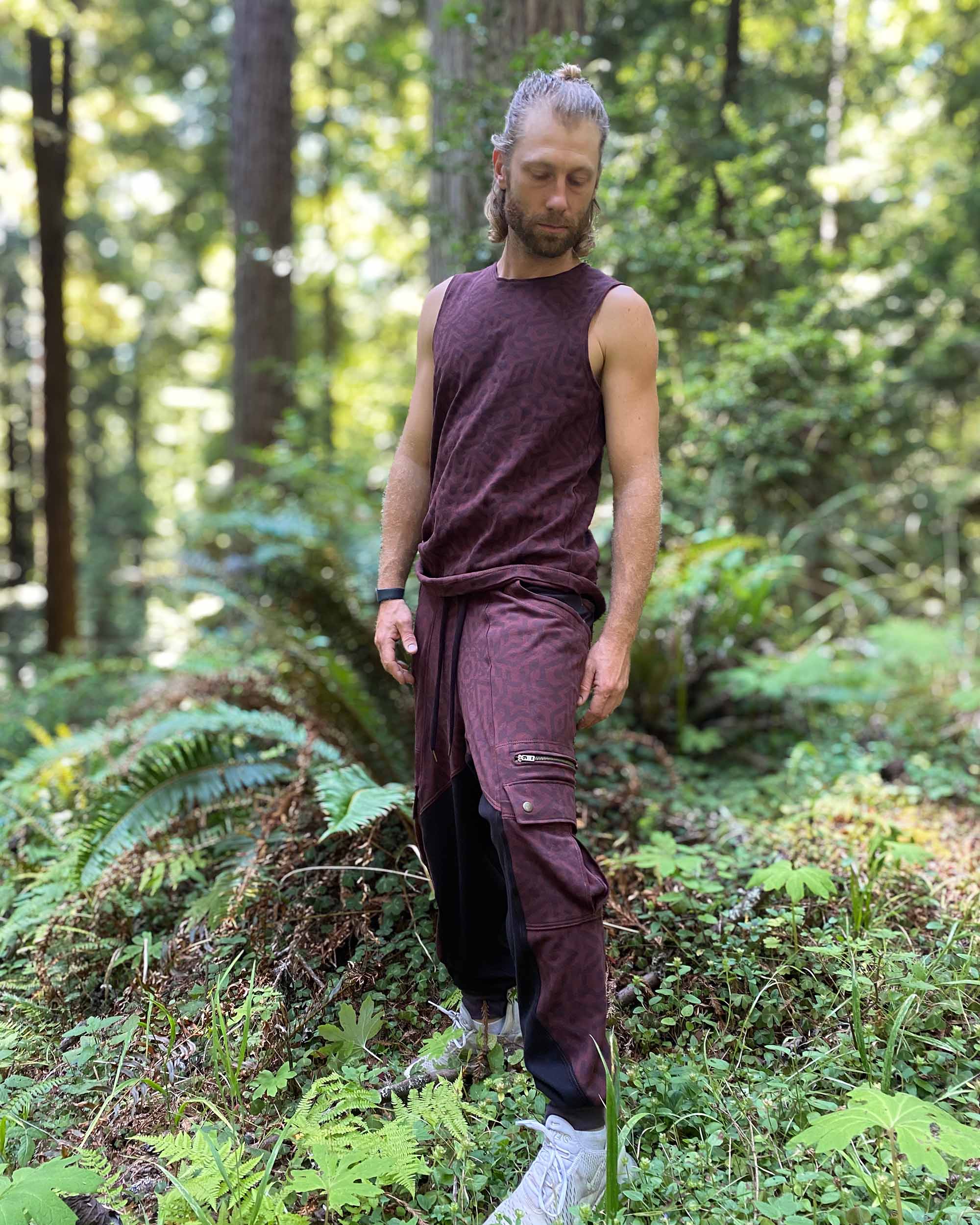 Organic cotton mens tank top, brown fabric with geometric print, right side view with model in nature.
