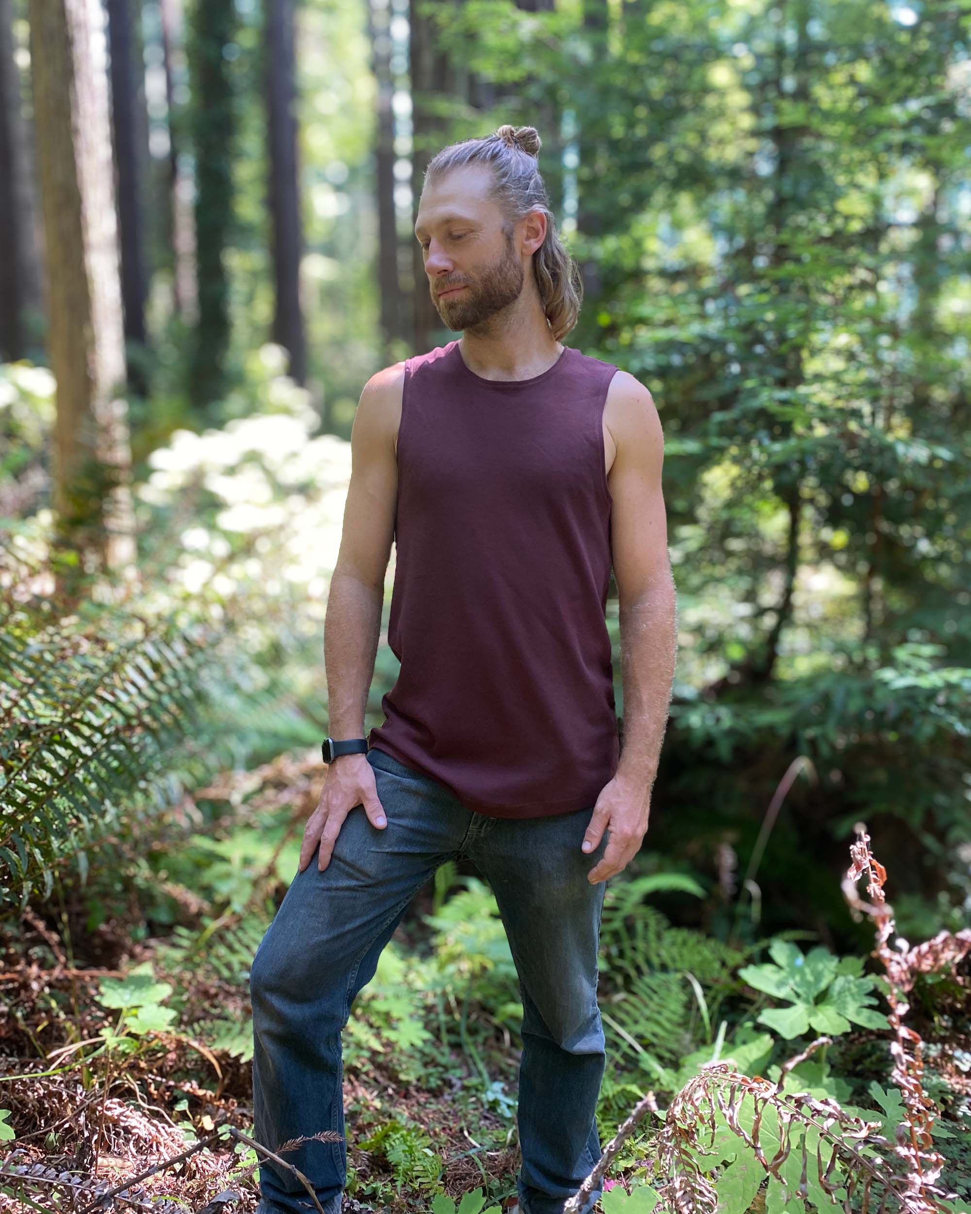 Organic cotton mens tank top, brown fabric, left side view on model in nature.