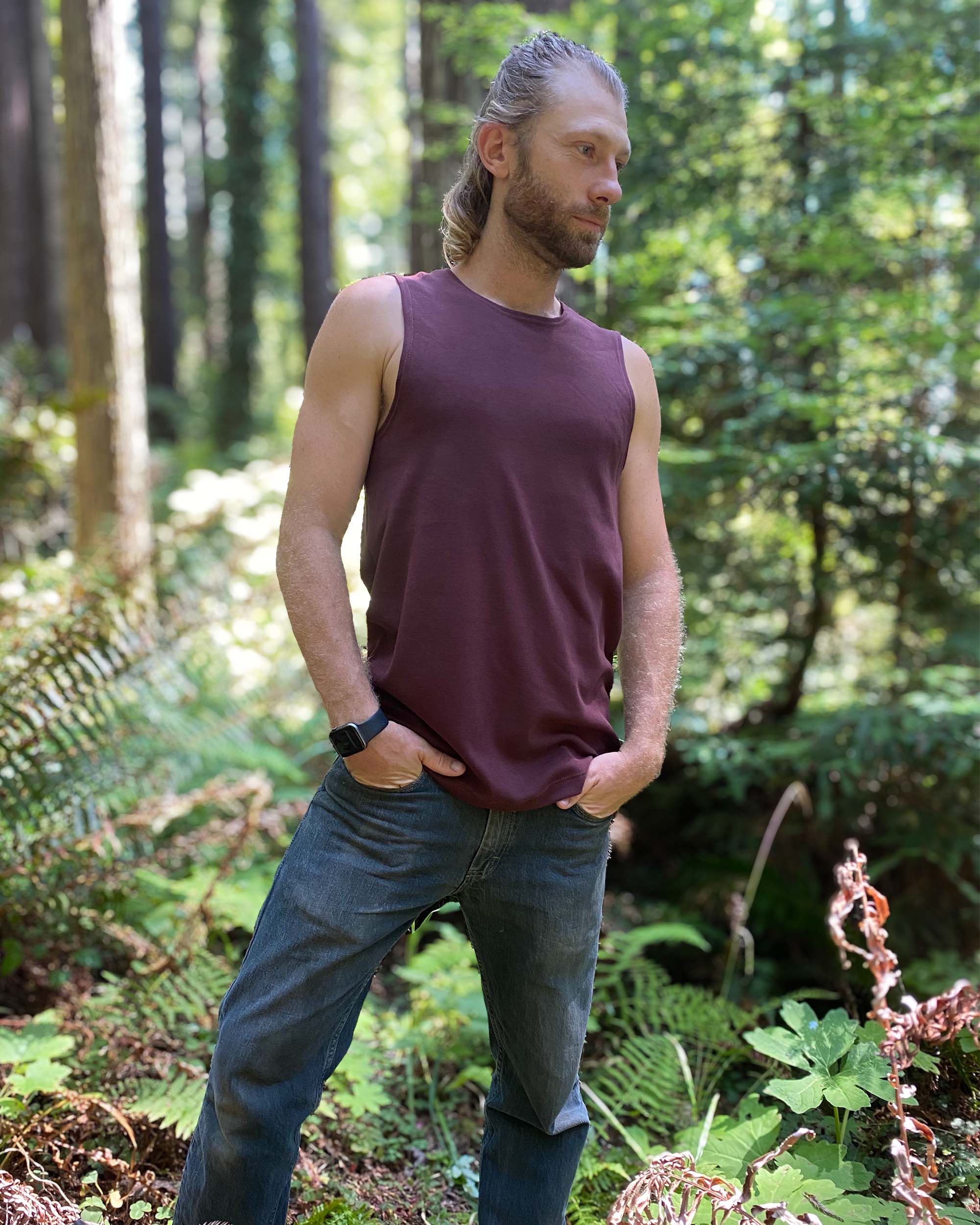 Organic cotton mens tank top, brown fabric, right side view on model in nature.