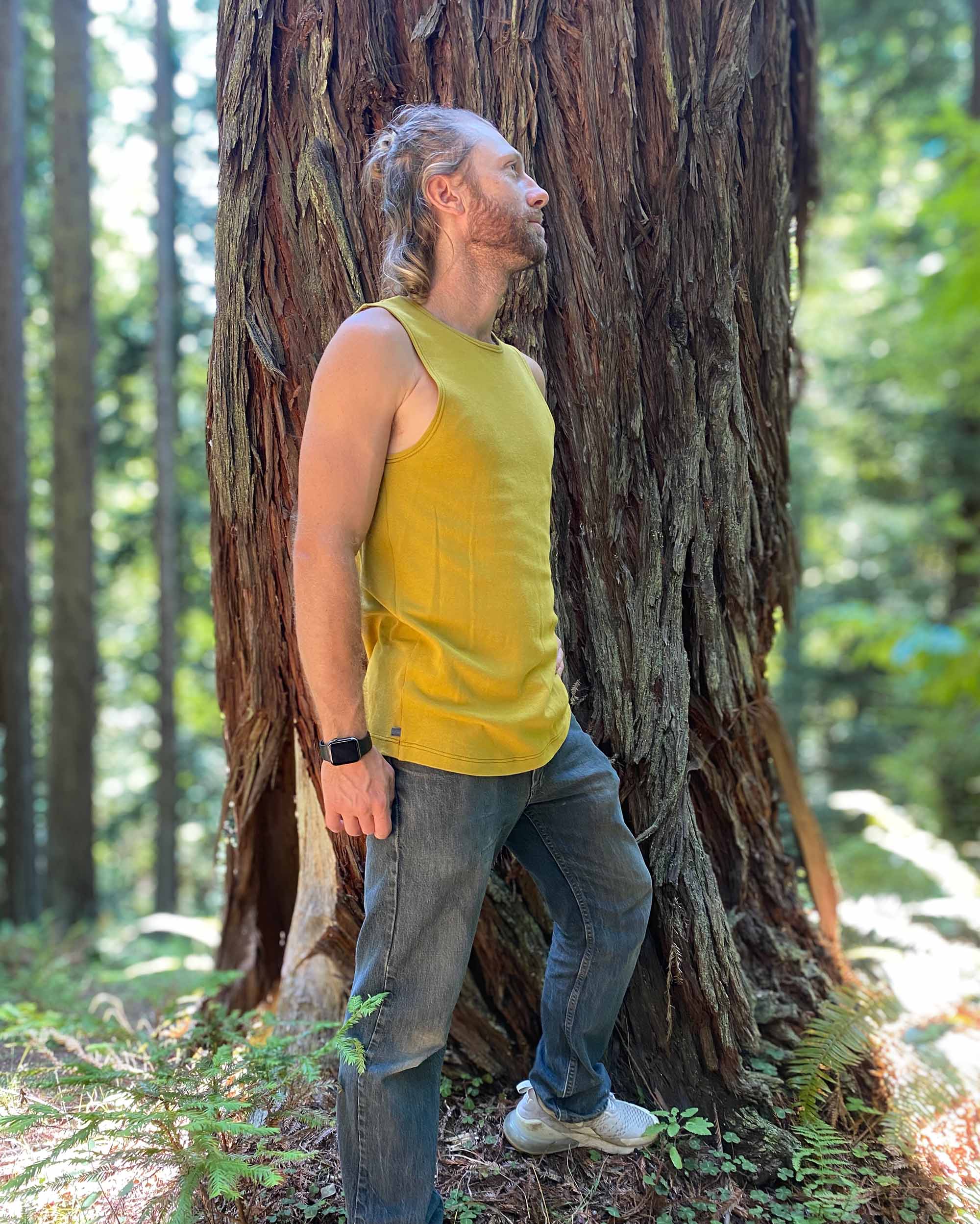 Organic cotton mens tank top, yellow fabric, side view on model in nature.