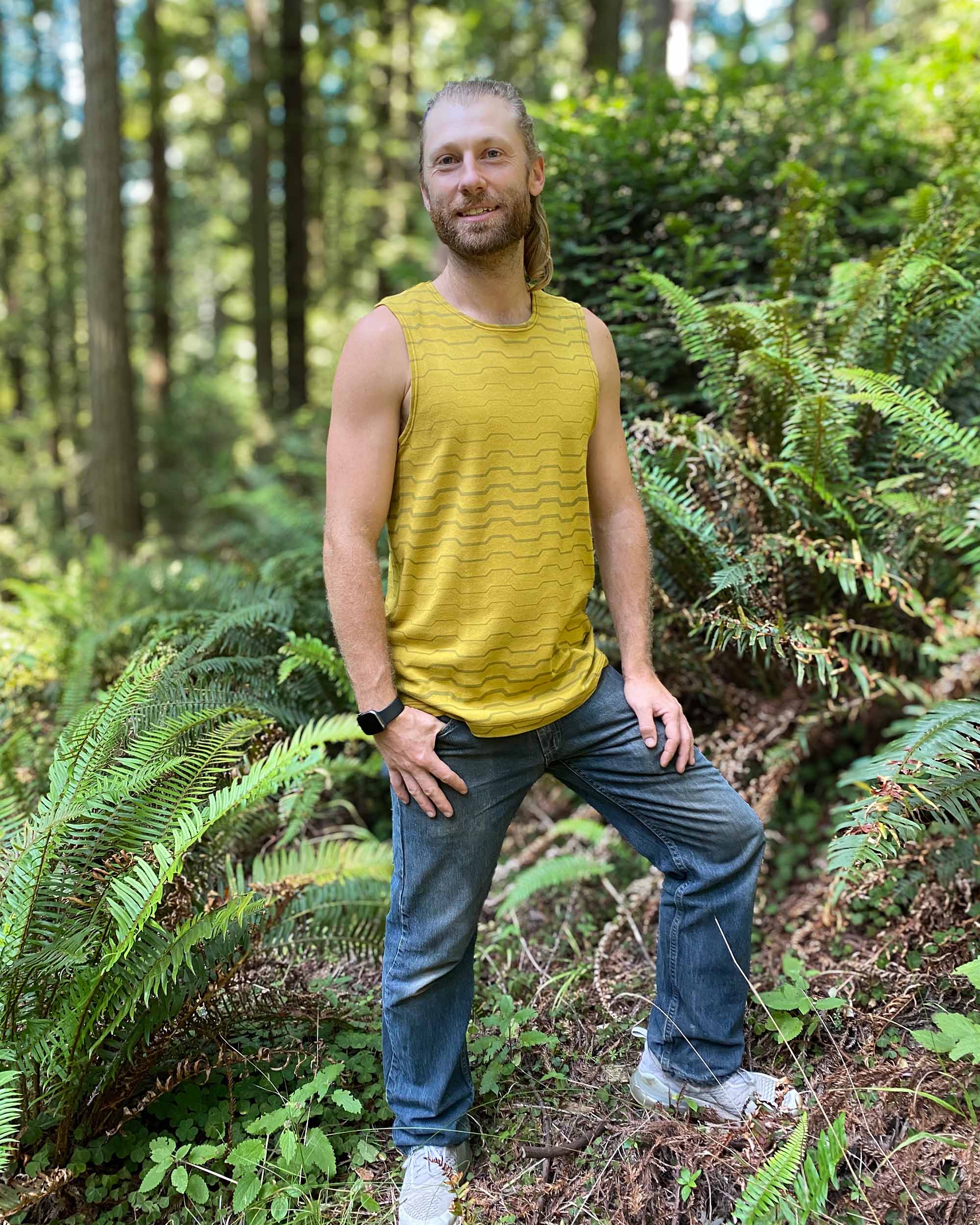 Organic cotton mens tank top, yellow fabric with geometric print, front view on model outdoors.