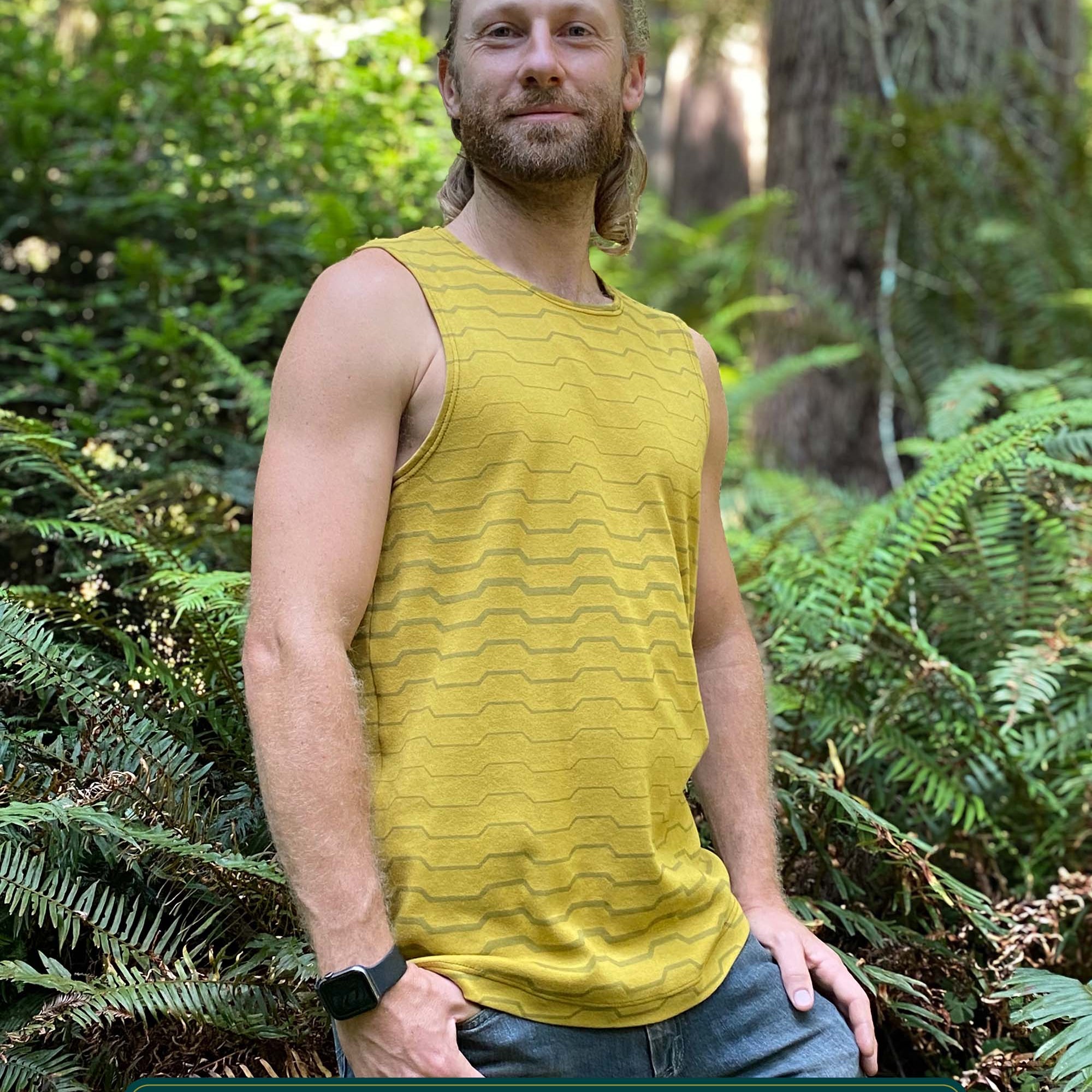 Organic cotton mens tank top, yellow fabric with geometric print, side view outdoors.