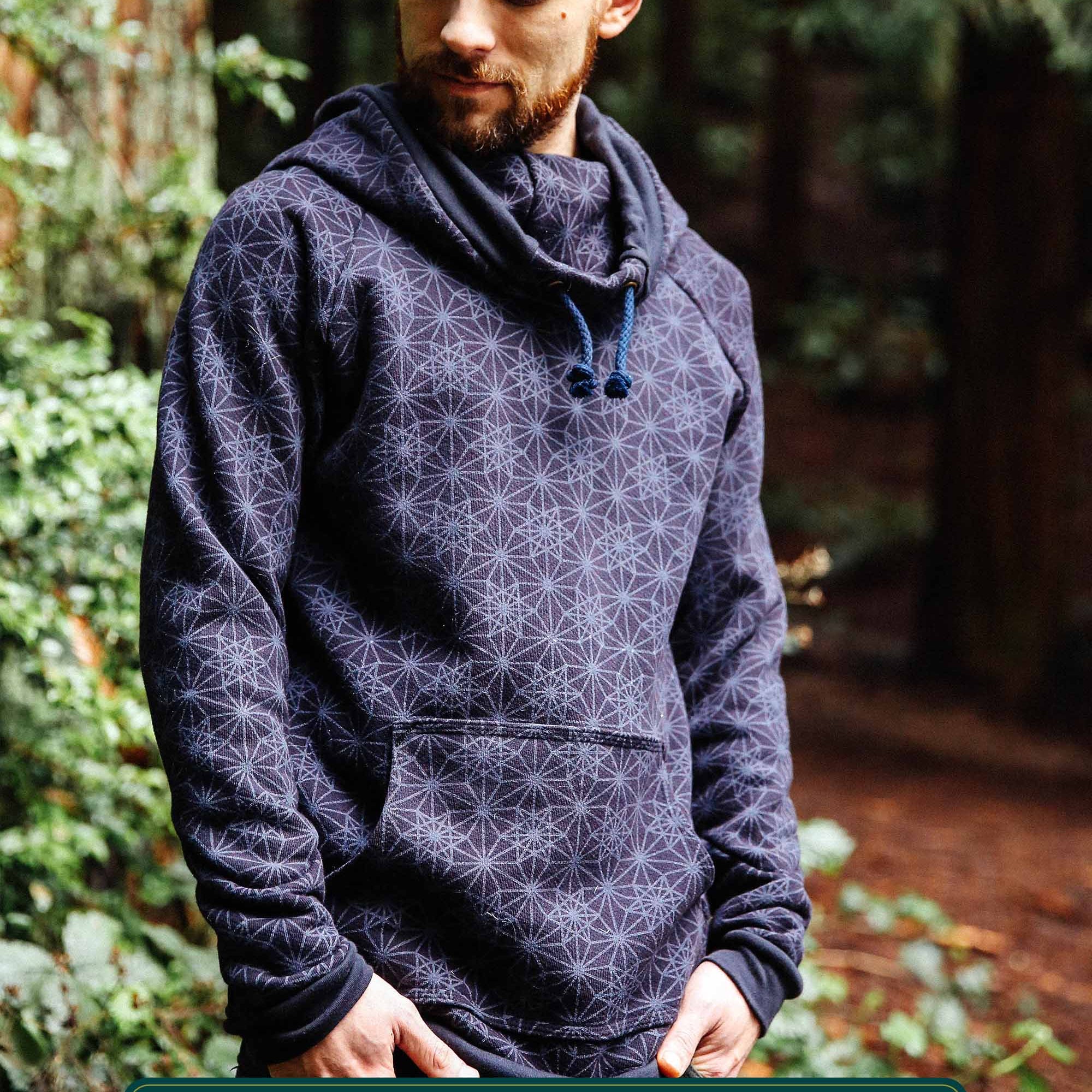 Organic cotton fleece unisex hoodie, black fabric with geometric print, front right view on male model in nature.