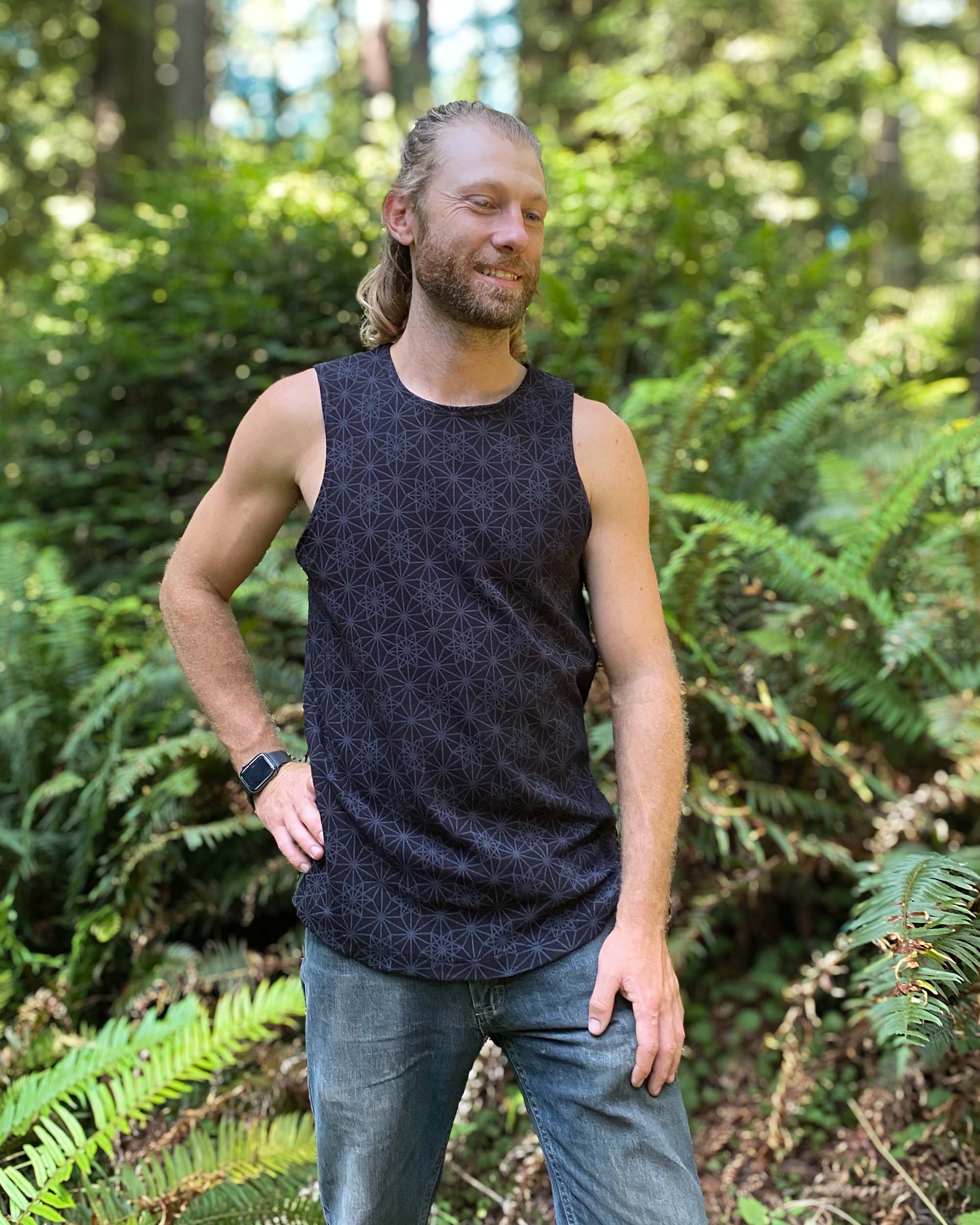 Organic cotton mens tank top, black fabric with geometric print, front view with model.