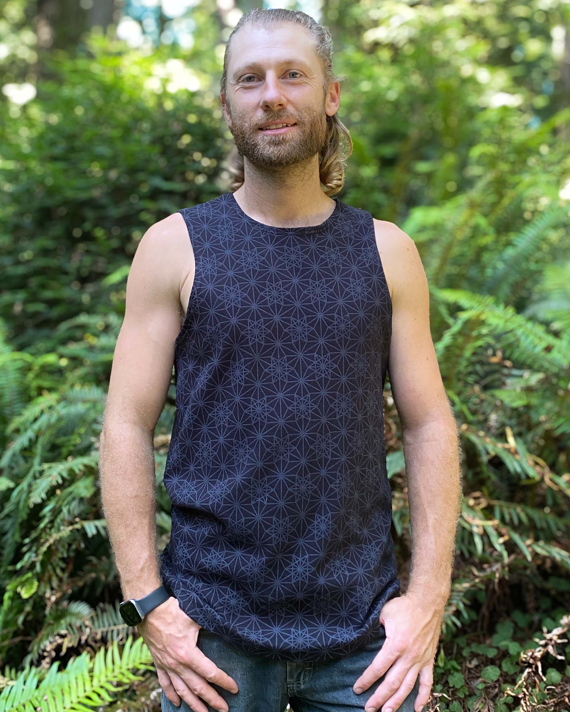 Organic cotton mens tank top, black geo print fabric, front view with model in natural light.