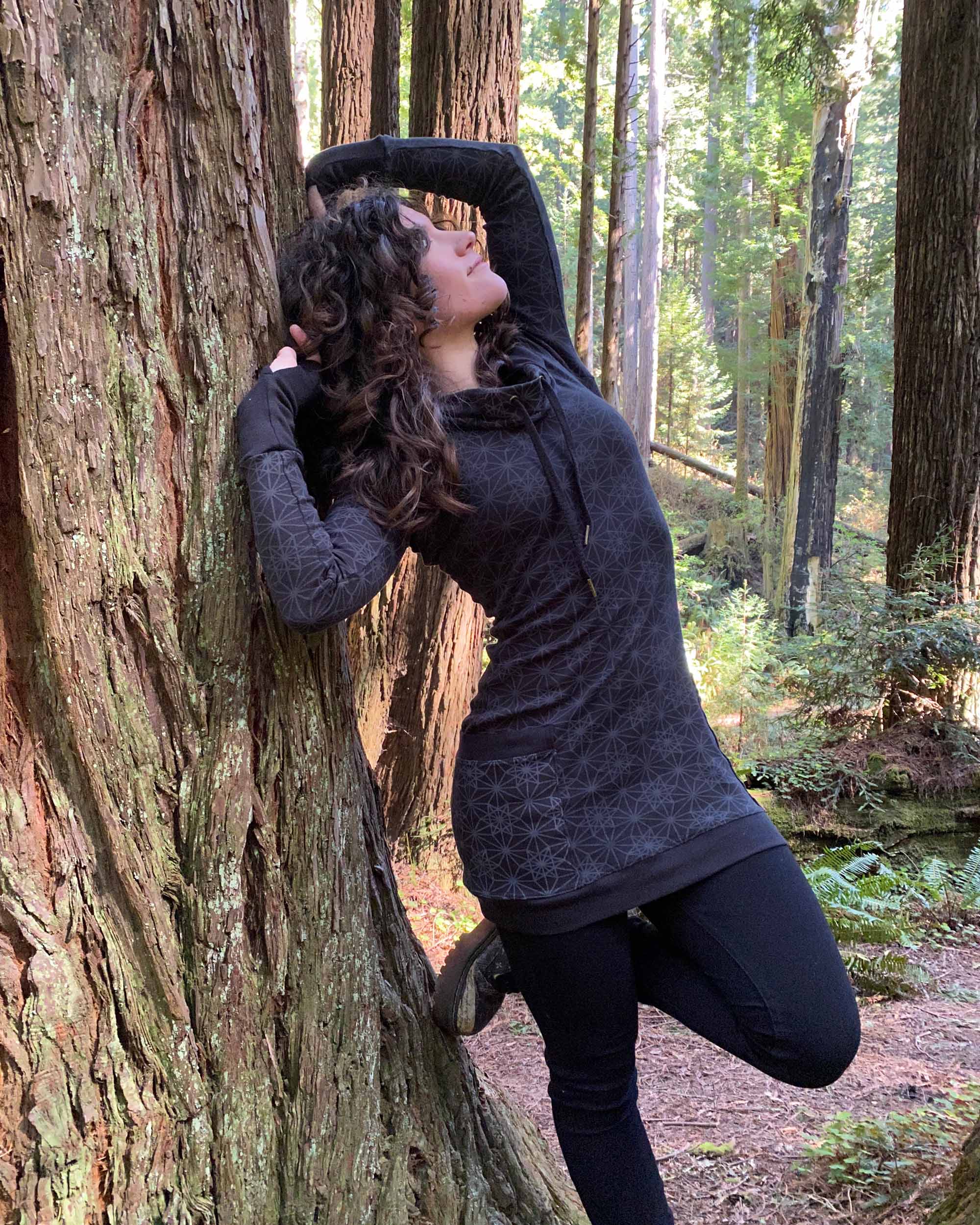 Organic cotton hooded long sleeve dress, black with geometric print, right side view on female model.