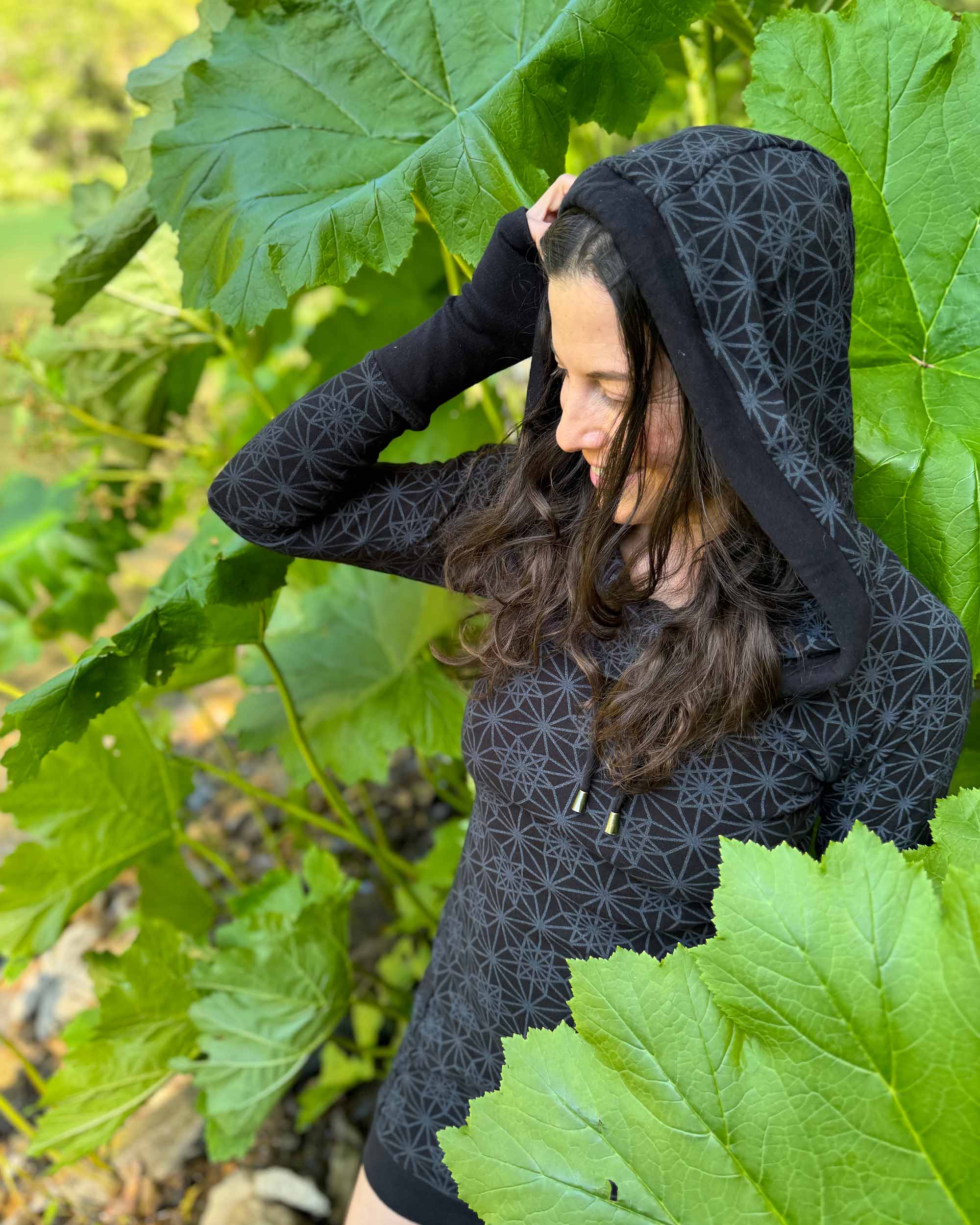 Organic cotton long sleeve tunic dress, black with sacred geometry print, top left side view on female model.