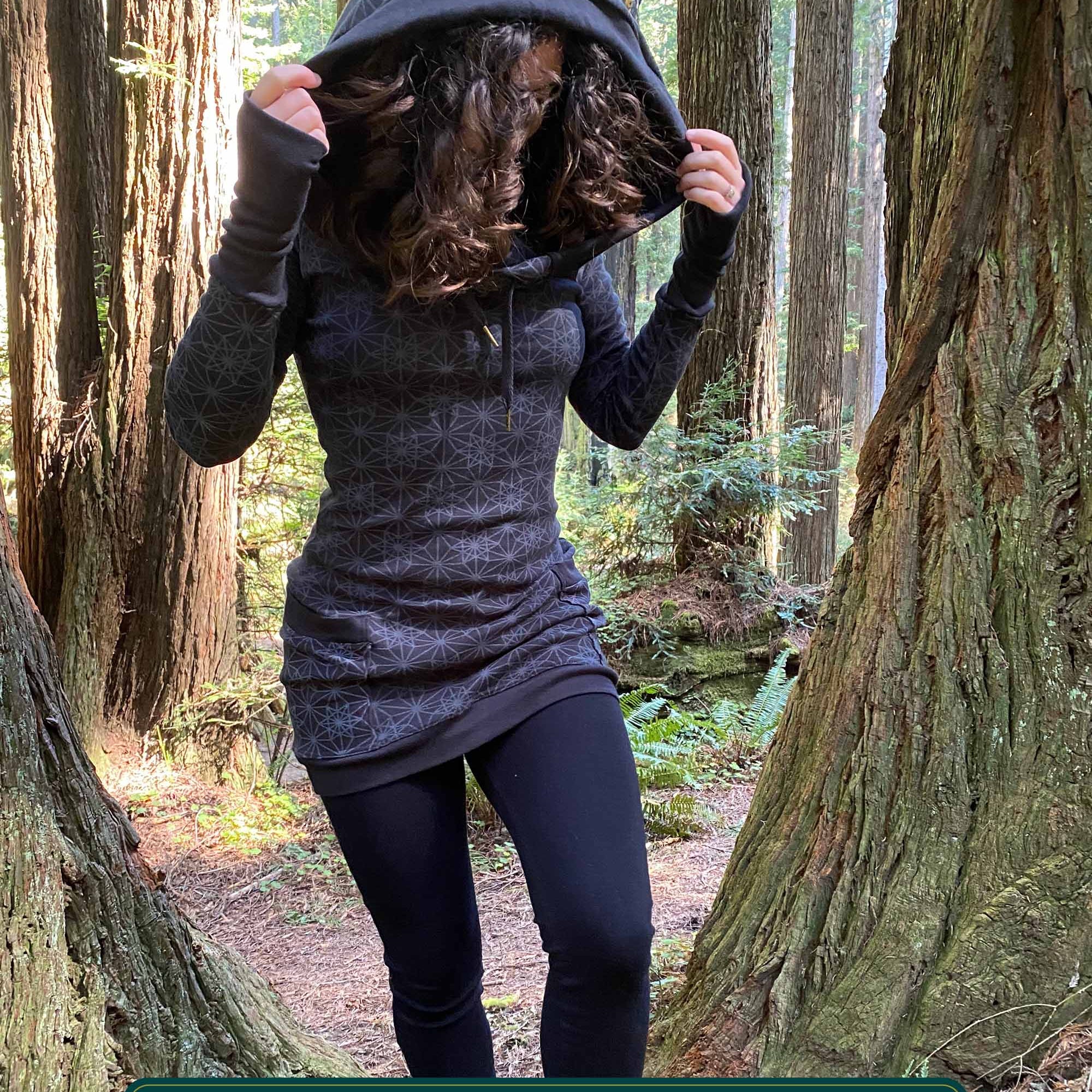 Organic cotton hooded long sleeve dress, black with geometric print, front view on female model.