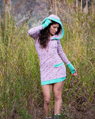 Organic cotton fitted tunic dress, pink with green accent fabric, front view on female model in nature.