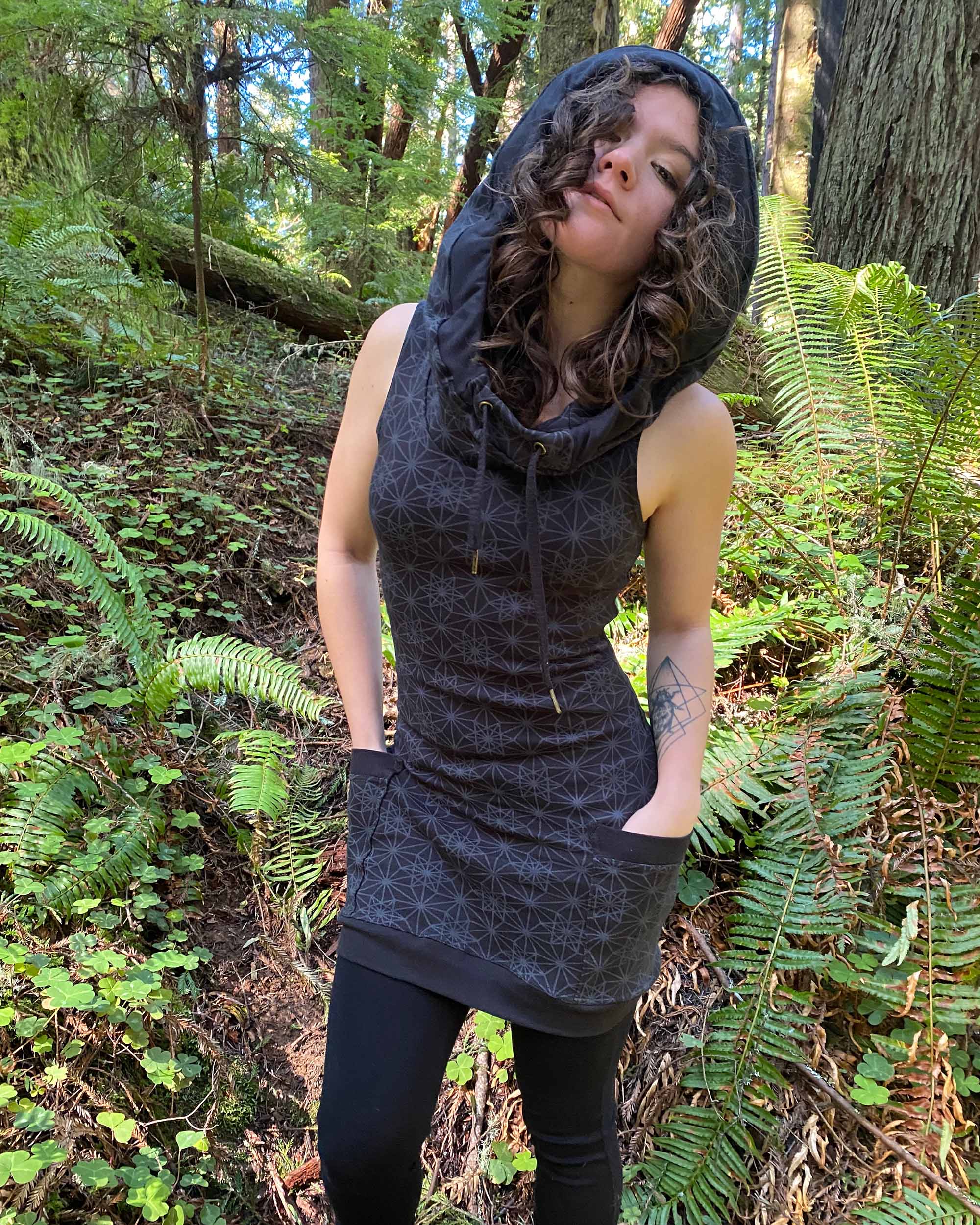 Organic cotton sleeveless tunic dress, black fabric with geometric print, front view on female model.