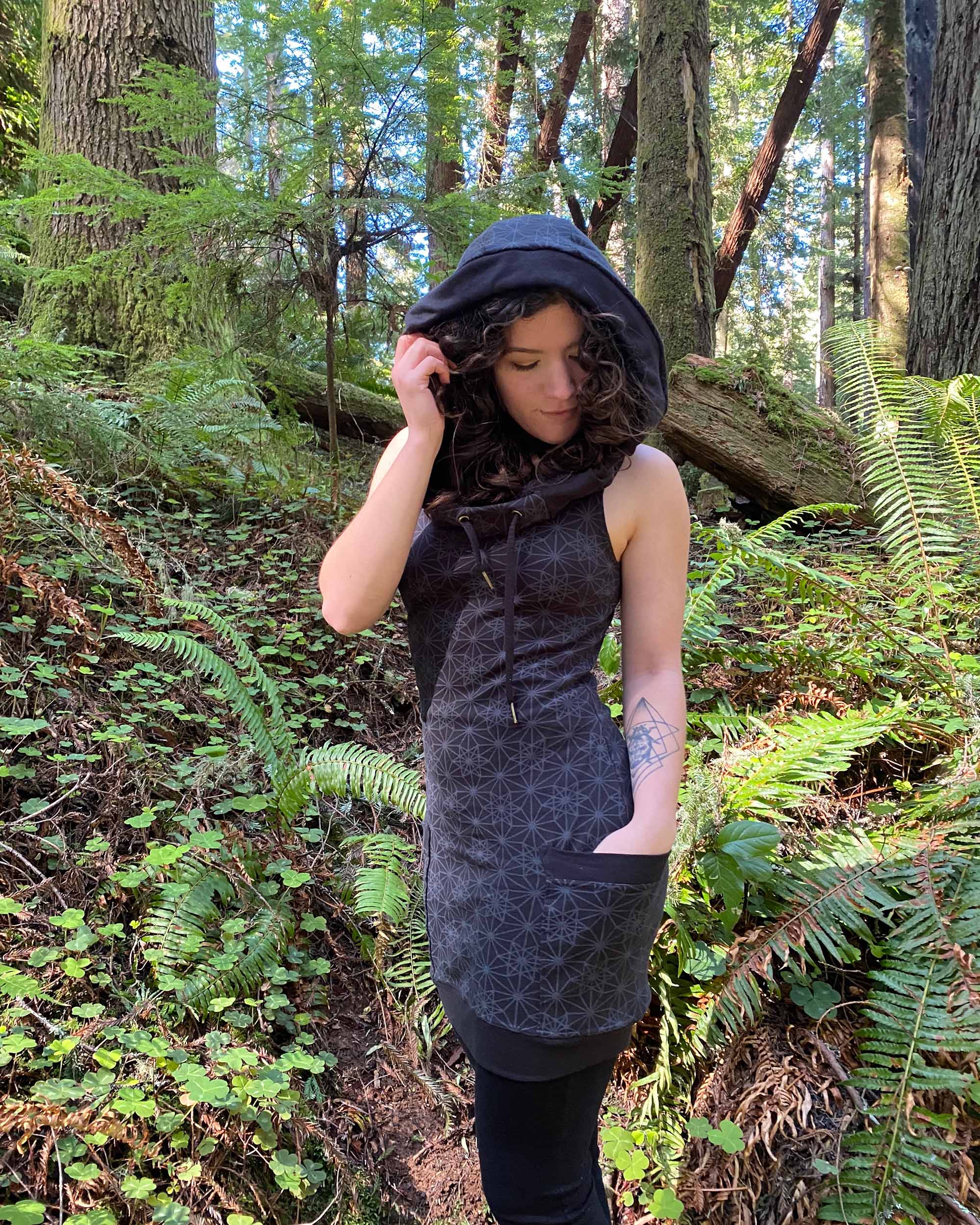 Organic cotton sleeveless tunic dress, black fabric with sacred geometry print, right side view worn by female model.