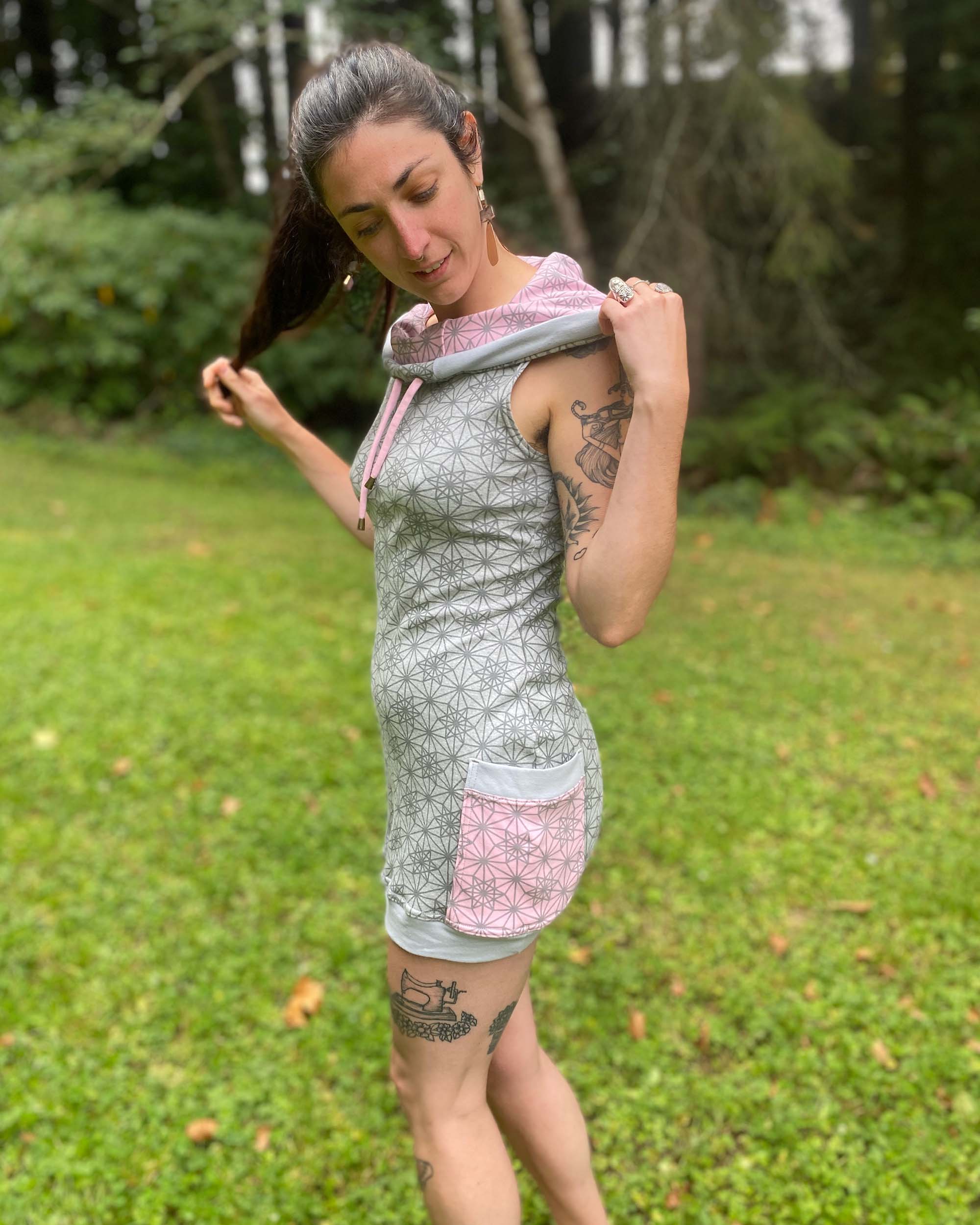 Organic cotton sleeveless tunic dress, grey fabric with geometric print, left side view on female model.