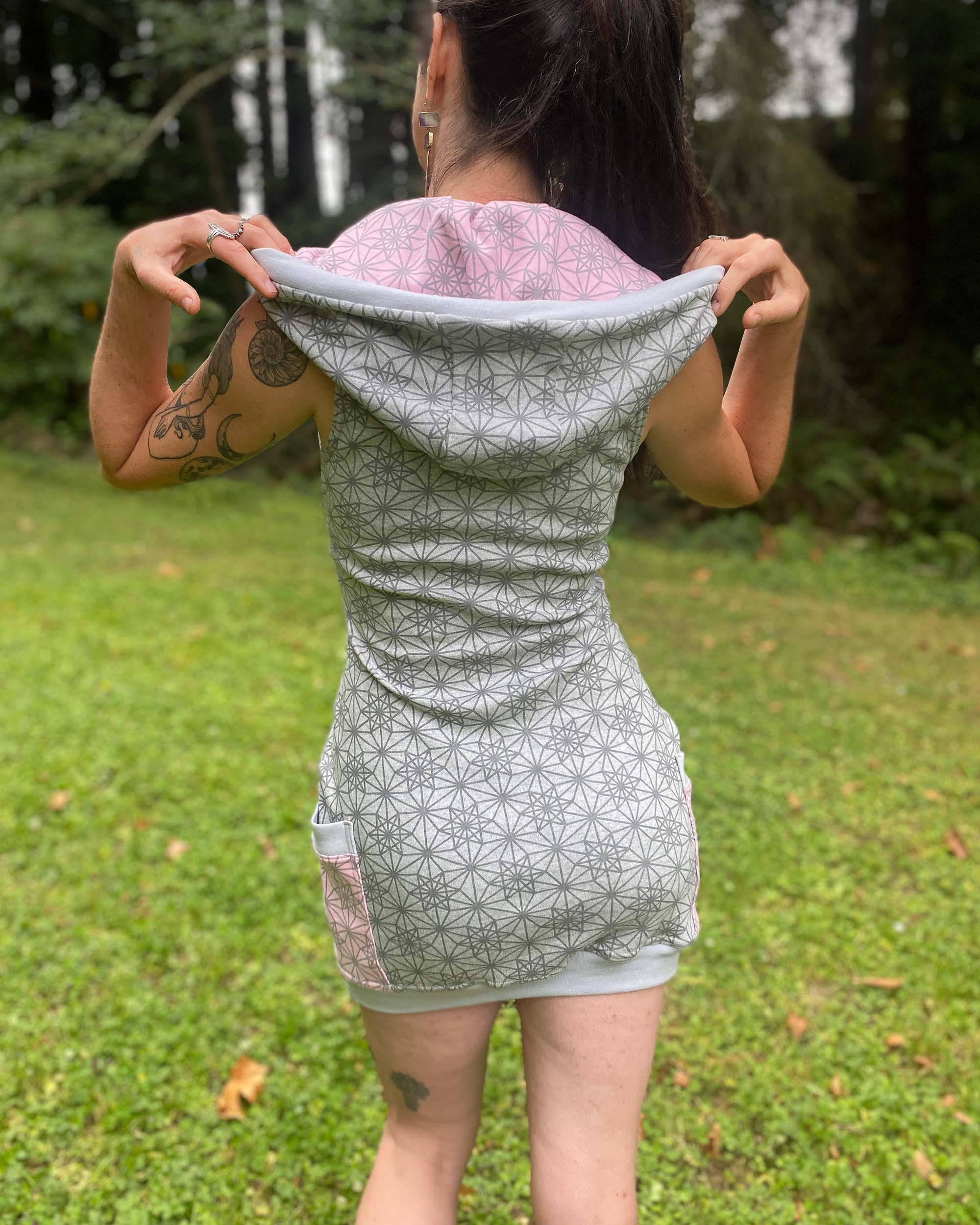 Organic cotton sleeveless tunic dress, grey fabric with geo print, back view on female model.