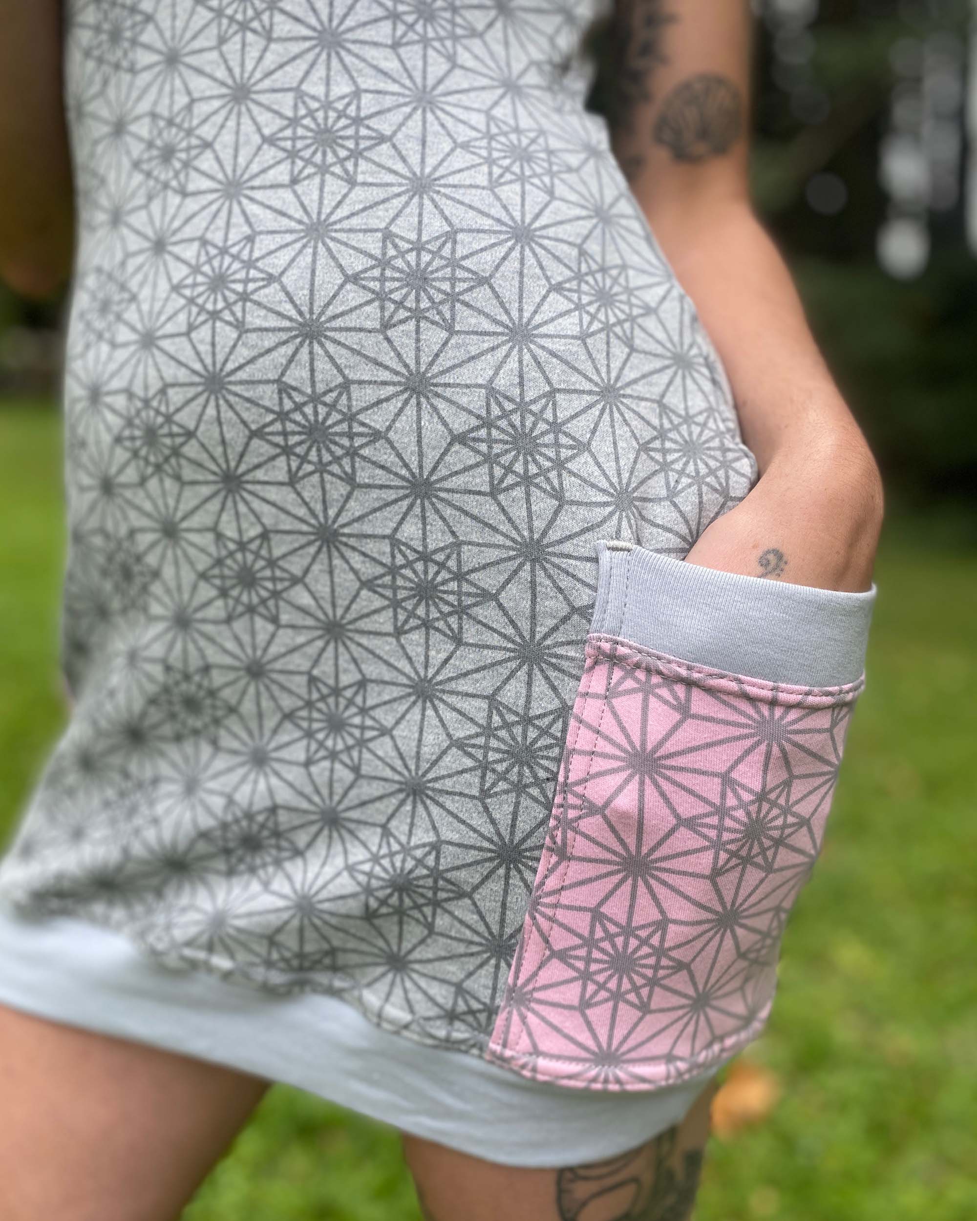 Organic cotton sleeveless tunic dress, grey fabric with pink accents, detail view of pocket.