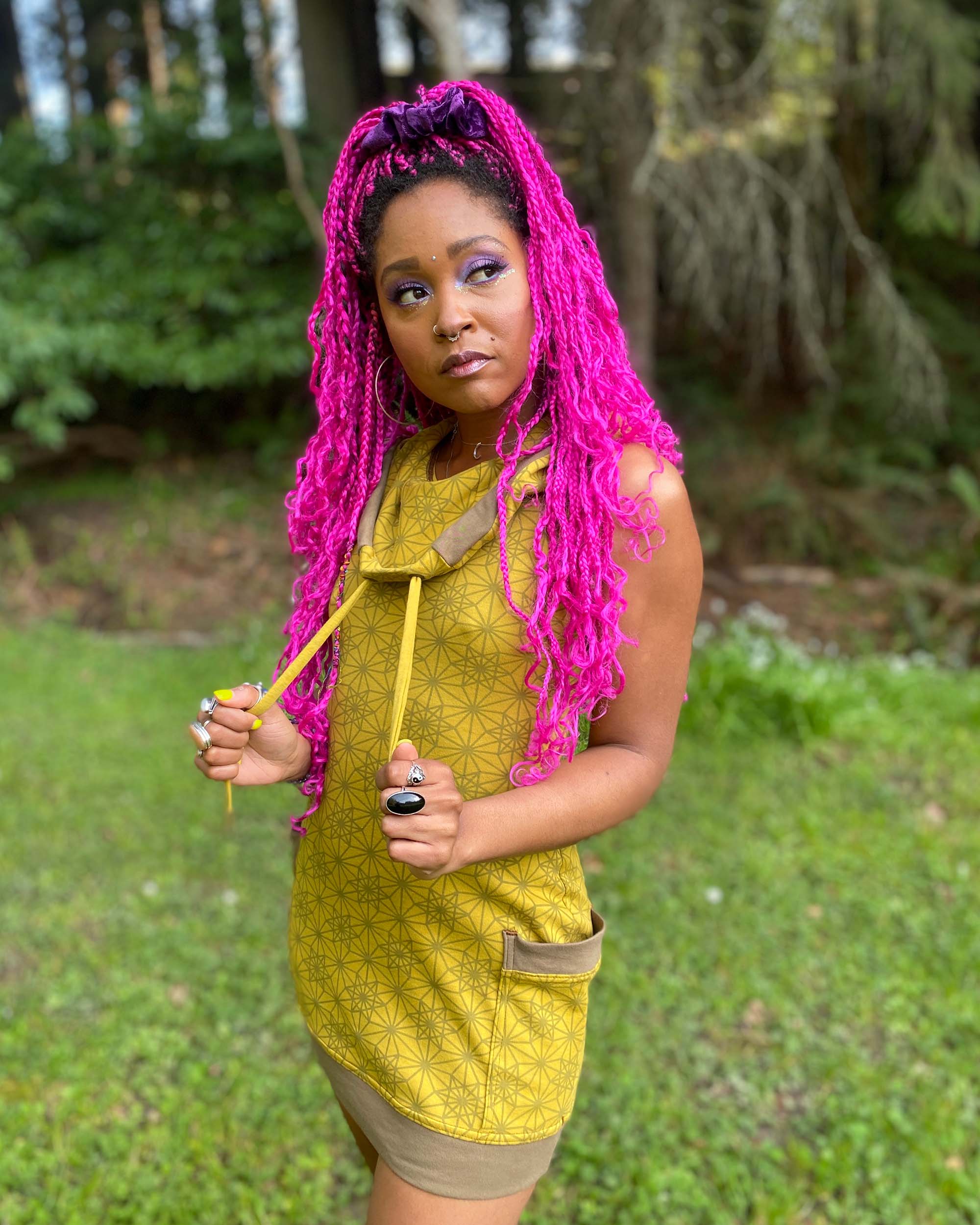 Organic cotton sleeveless tunic dress, yellow fabric with geometric print, front left side view on female model.