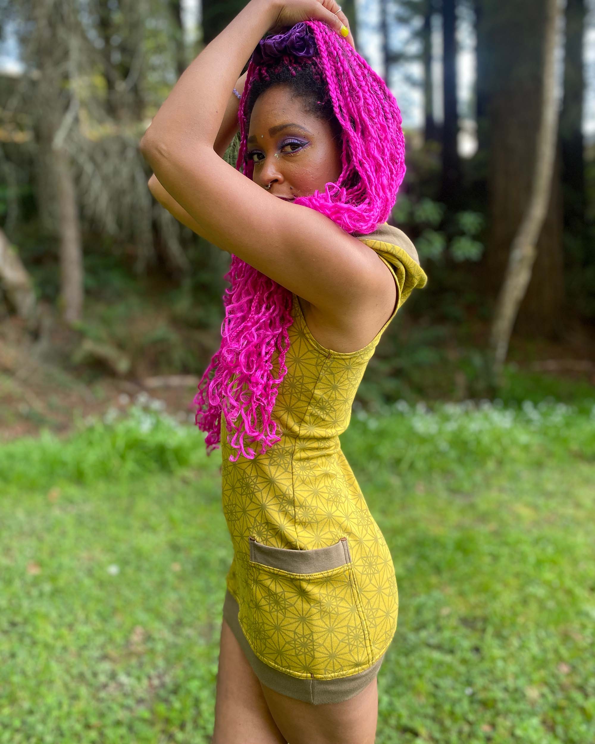 Organic cotton sleeveless tunic dress, yellow fabric with geo print, left side view on female model.