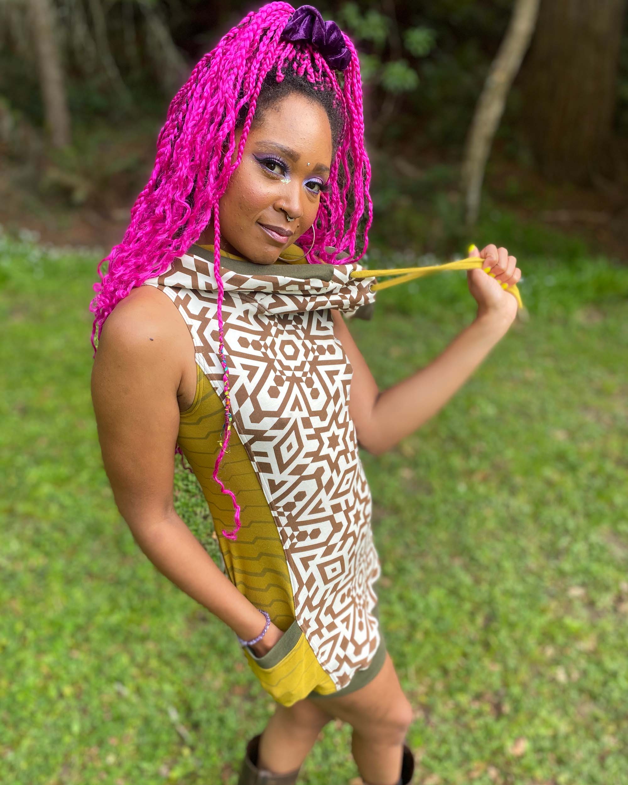 Sleeveless hooded tunic dress, natural fabric color with brown geometric print, right side view on female model.