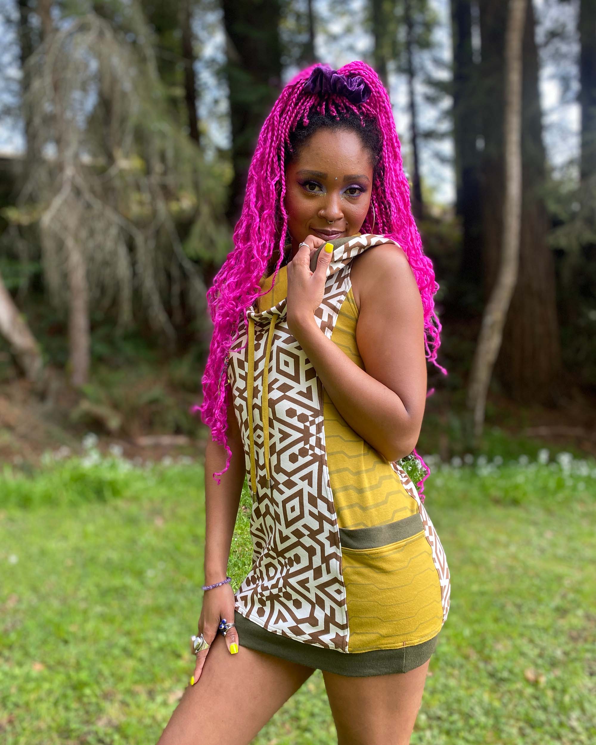 Organic cotton sleeveless hooded dress, natural fabric color with brown print, right side view of female model.