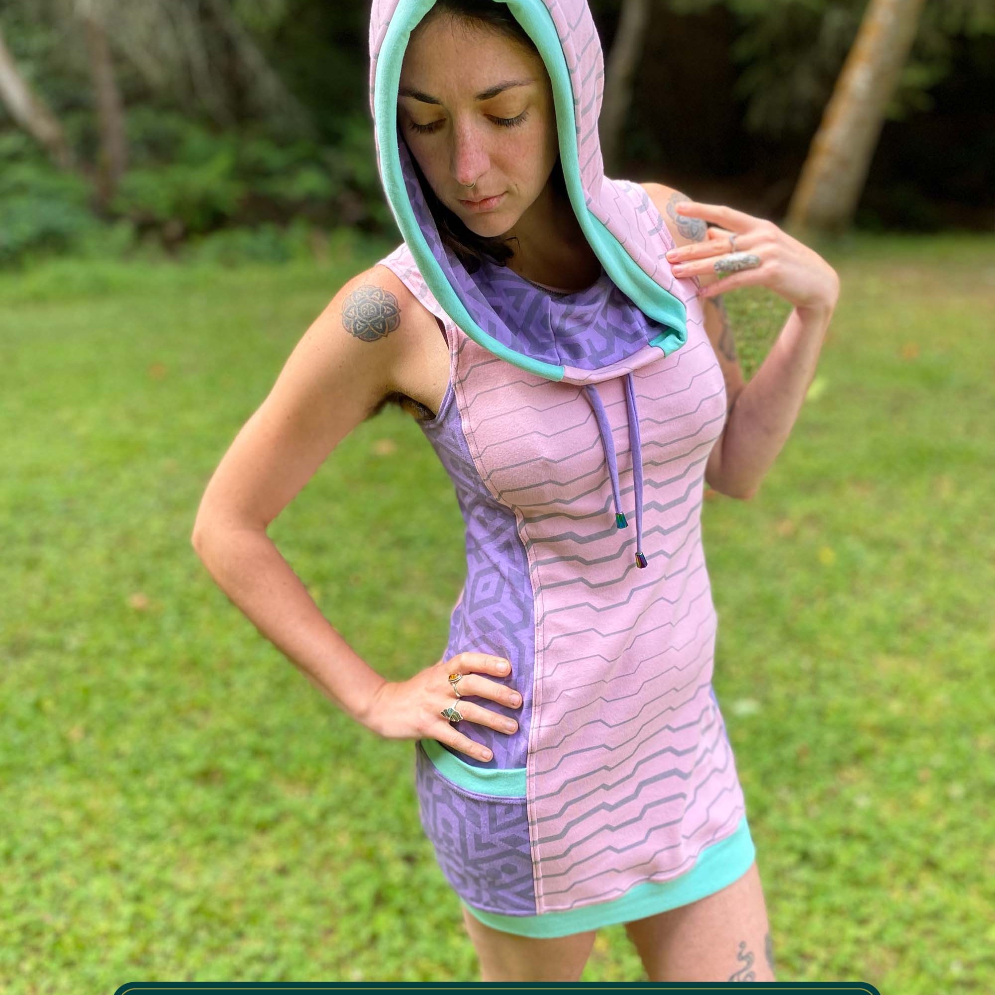Organic cotton sleeveless hooded dress, pink with lavender colored accents, front view on female model.