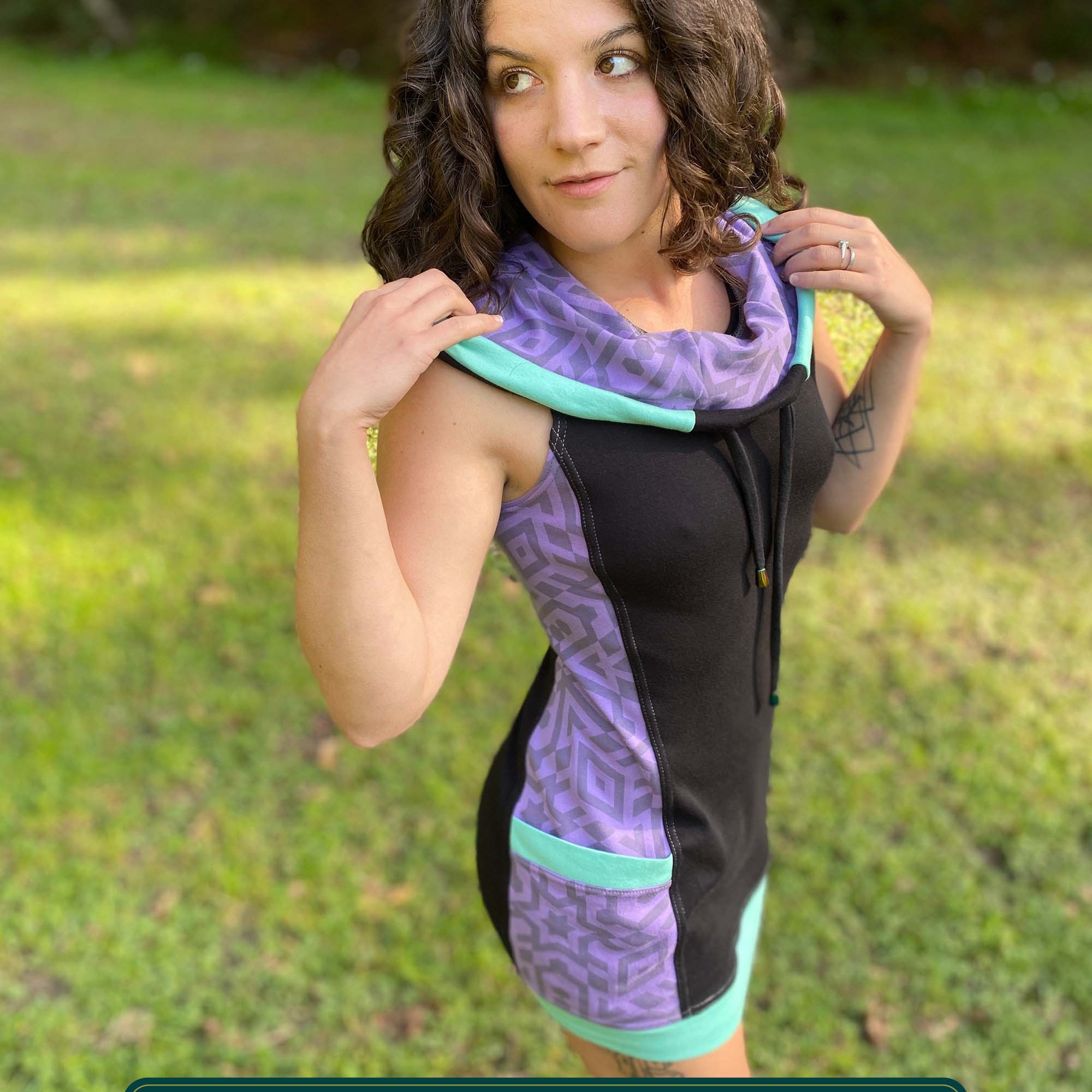 Organic cotton sleeveless hooded dress, black with lavender fabric accents, right front side view on female model.