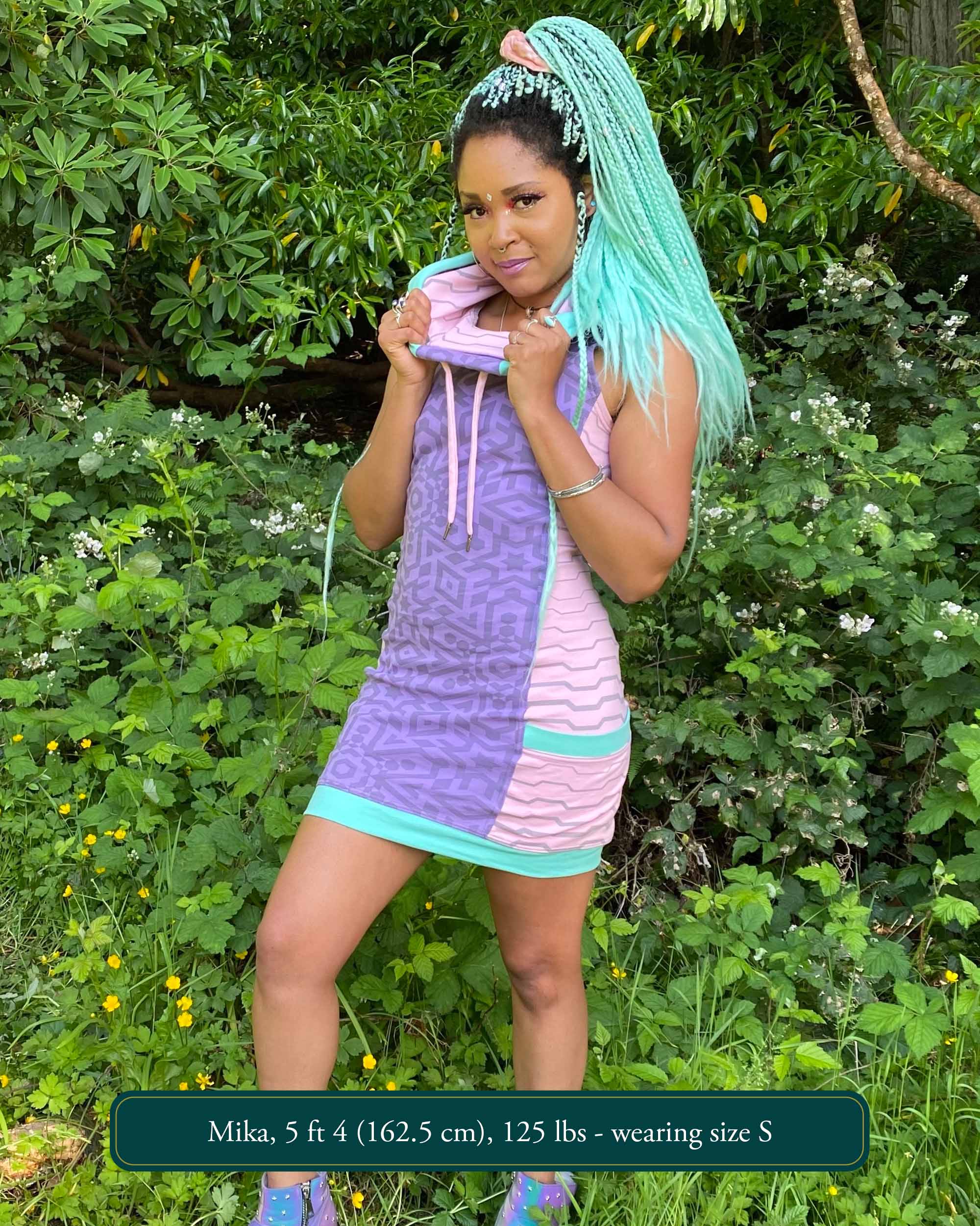 Organic cotton sleeveless hooded dress, lavender fabric with pink accents, front view worn by female model.