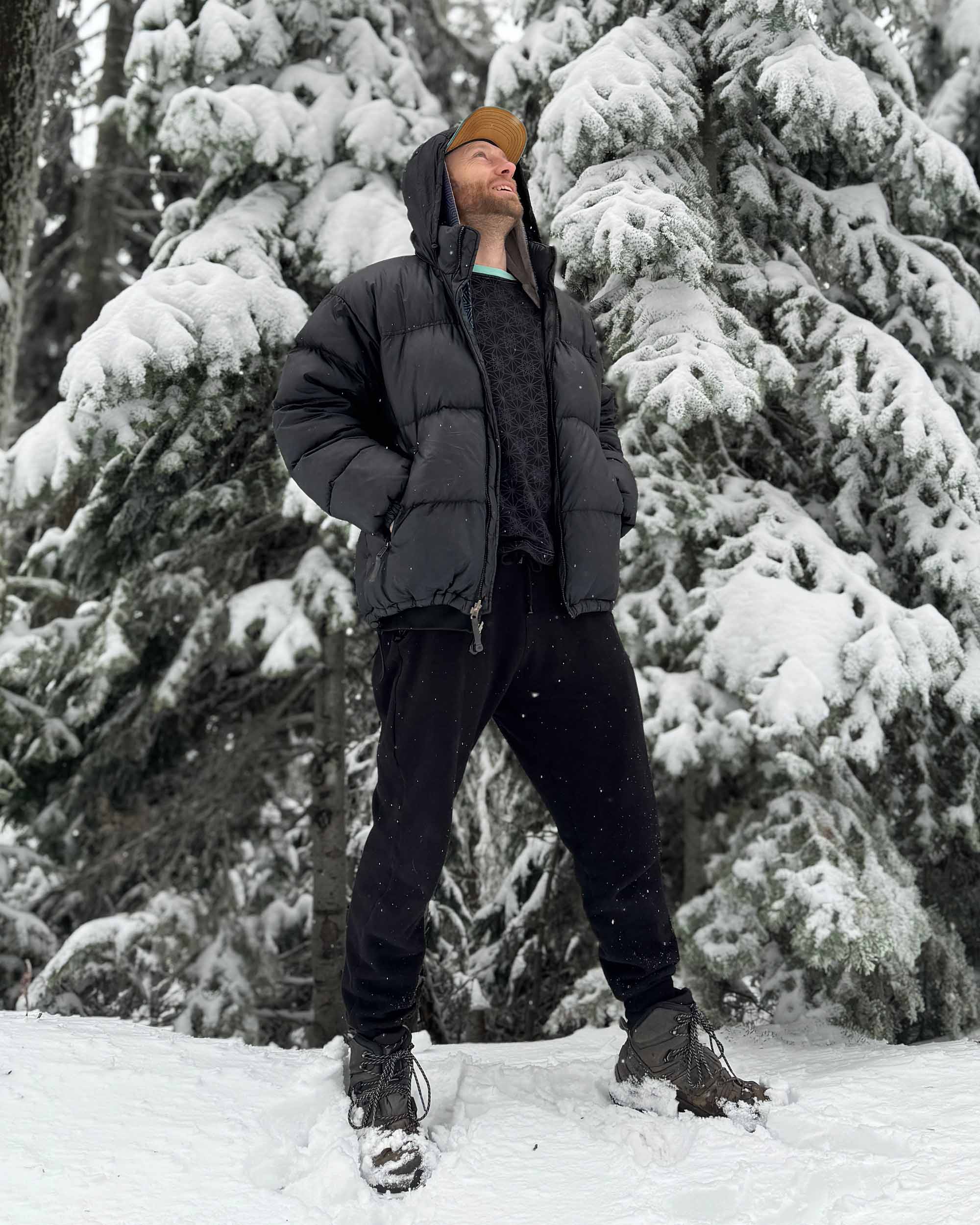 Organic cotton fleece joggers, solid black fabric, right side view on male model in the snow.