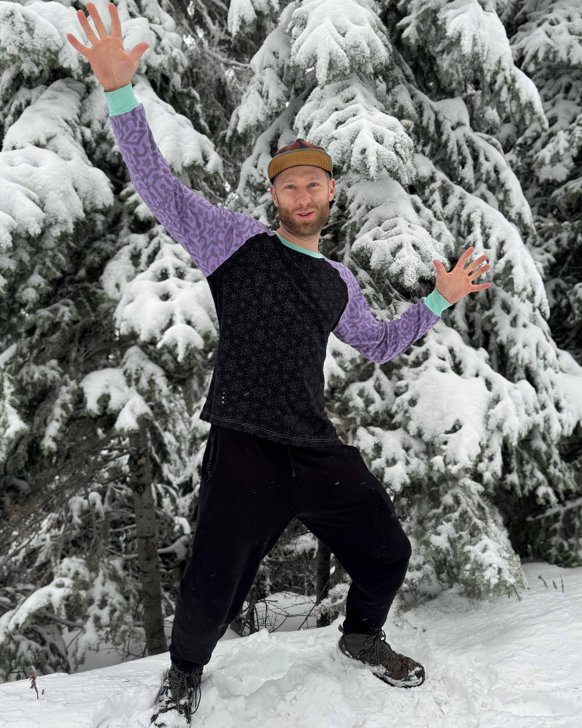 Organic cotton fleece joggers, solid black fabric, front view on male model playing in the snow.