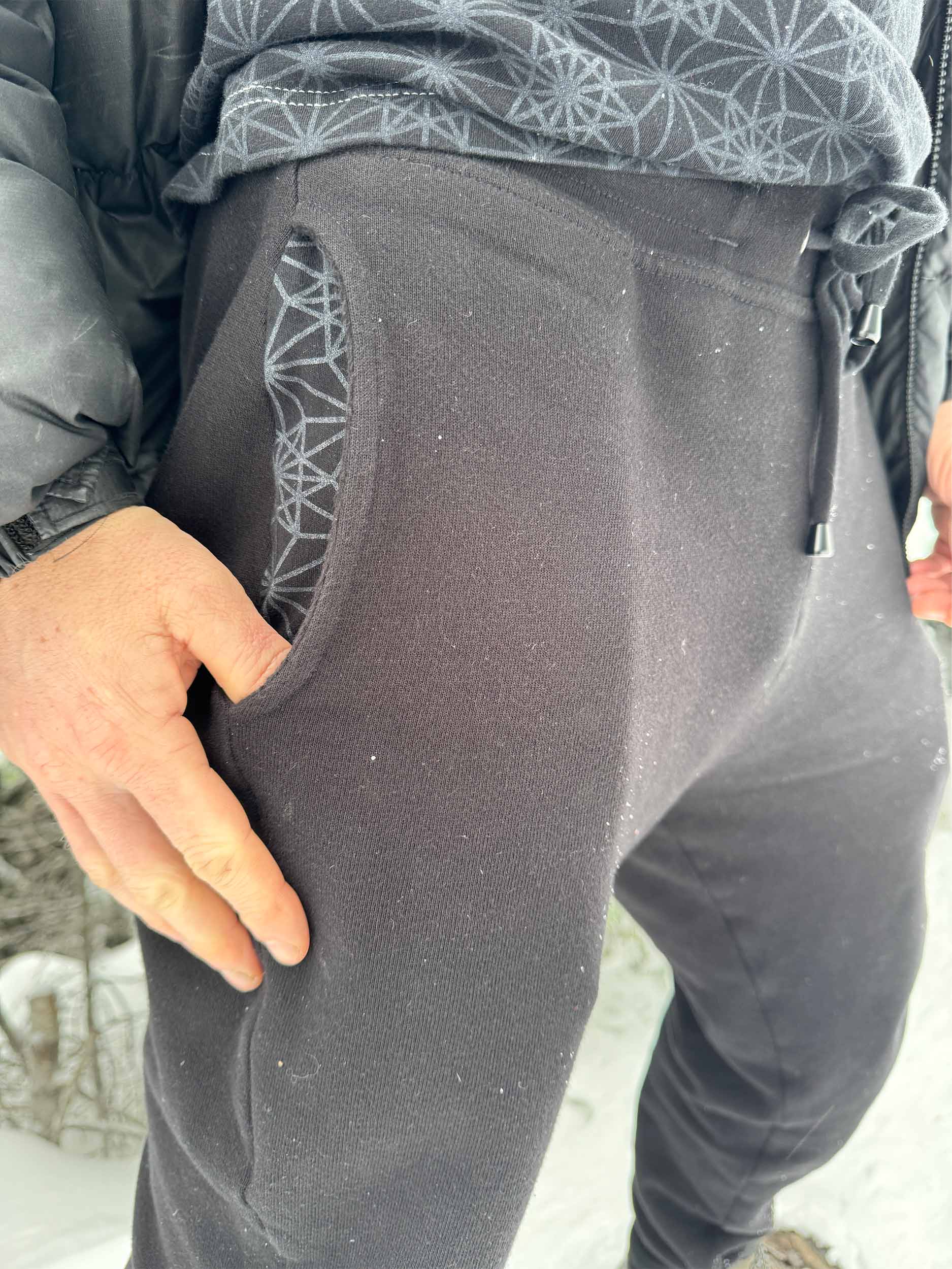 Organic cotton fleece joggers, solid black fabric, detail view of the pocket.