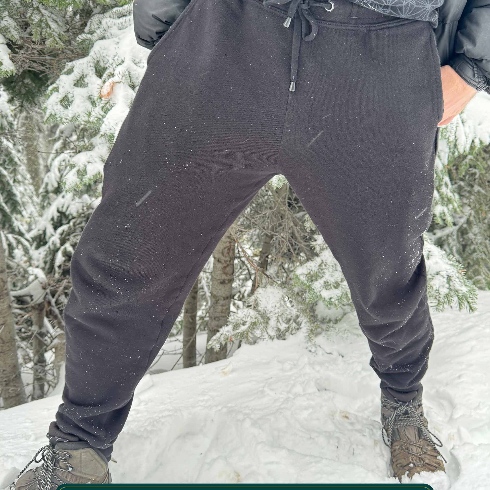 Organic cotton fleece joggers, solid black fabric, front view on male model in the snow.