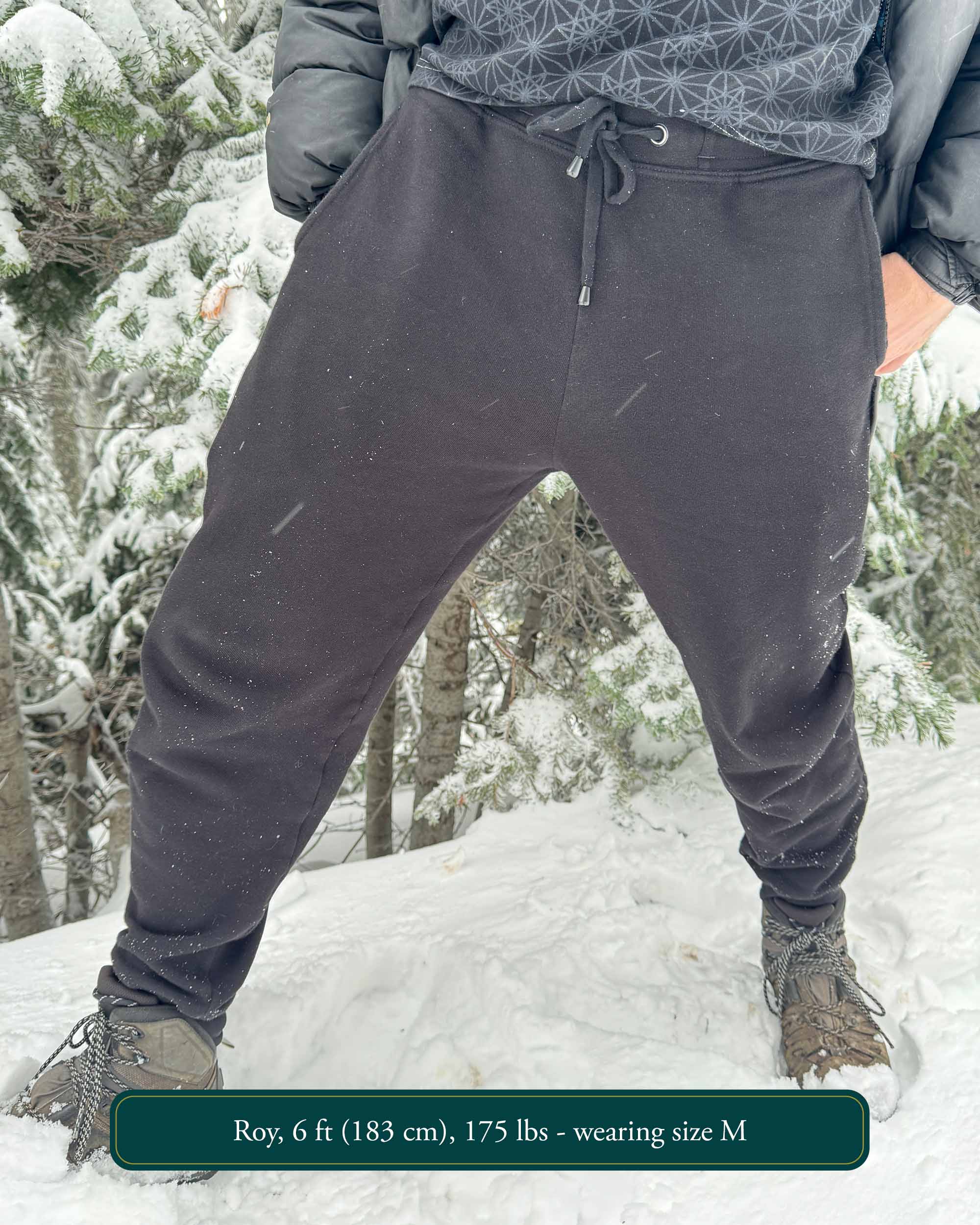 Organic cotton fleece joggers, solid black fabric, front view on male model in the snow.
