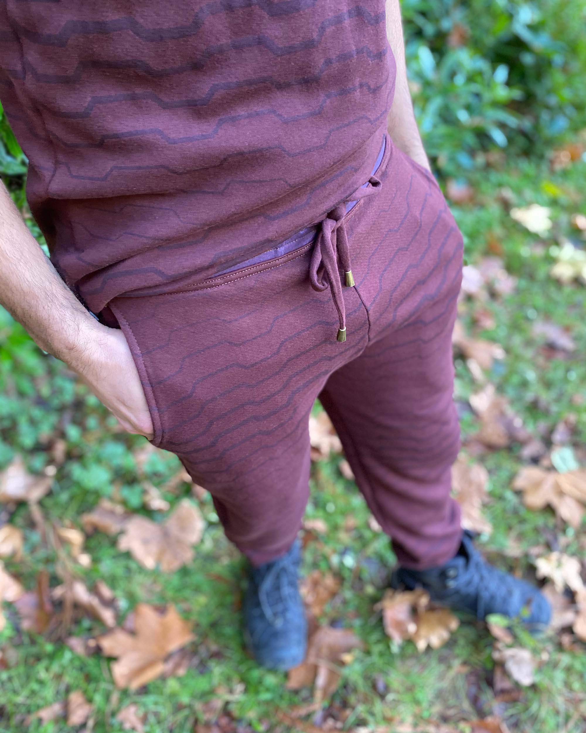 Organic cotton fleece joggers, reddish brown fabric with geometric all over print, detail view on male model.