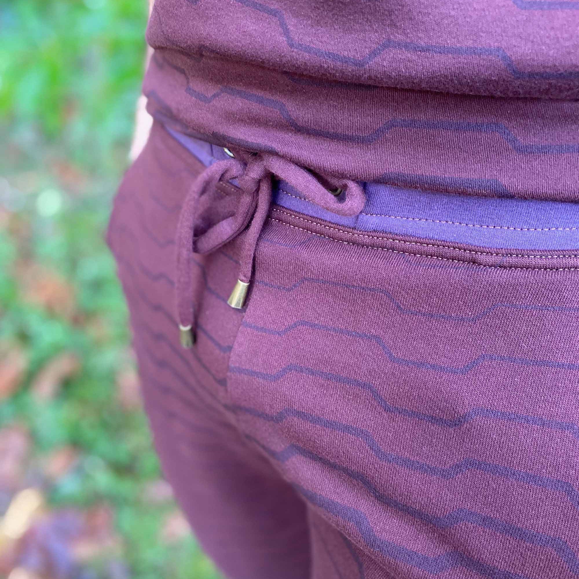 Organic cotton fleece joggers, reddish brown fabric with geometric all over print, detail front view of drawcord.