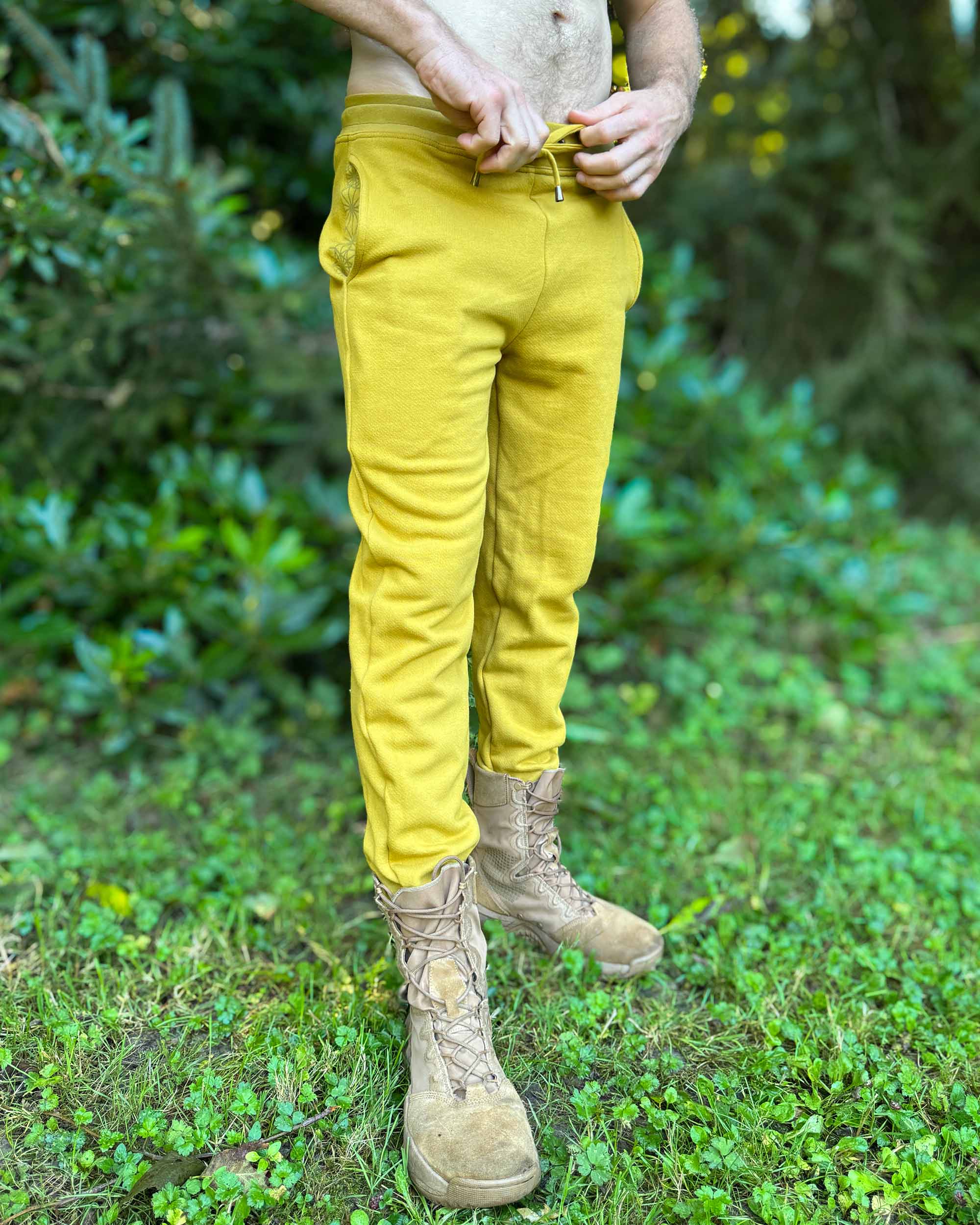 Organic cotton fleece joggers, solid yellow fabric, front side view on male model in nature.