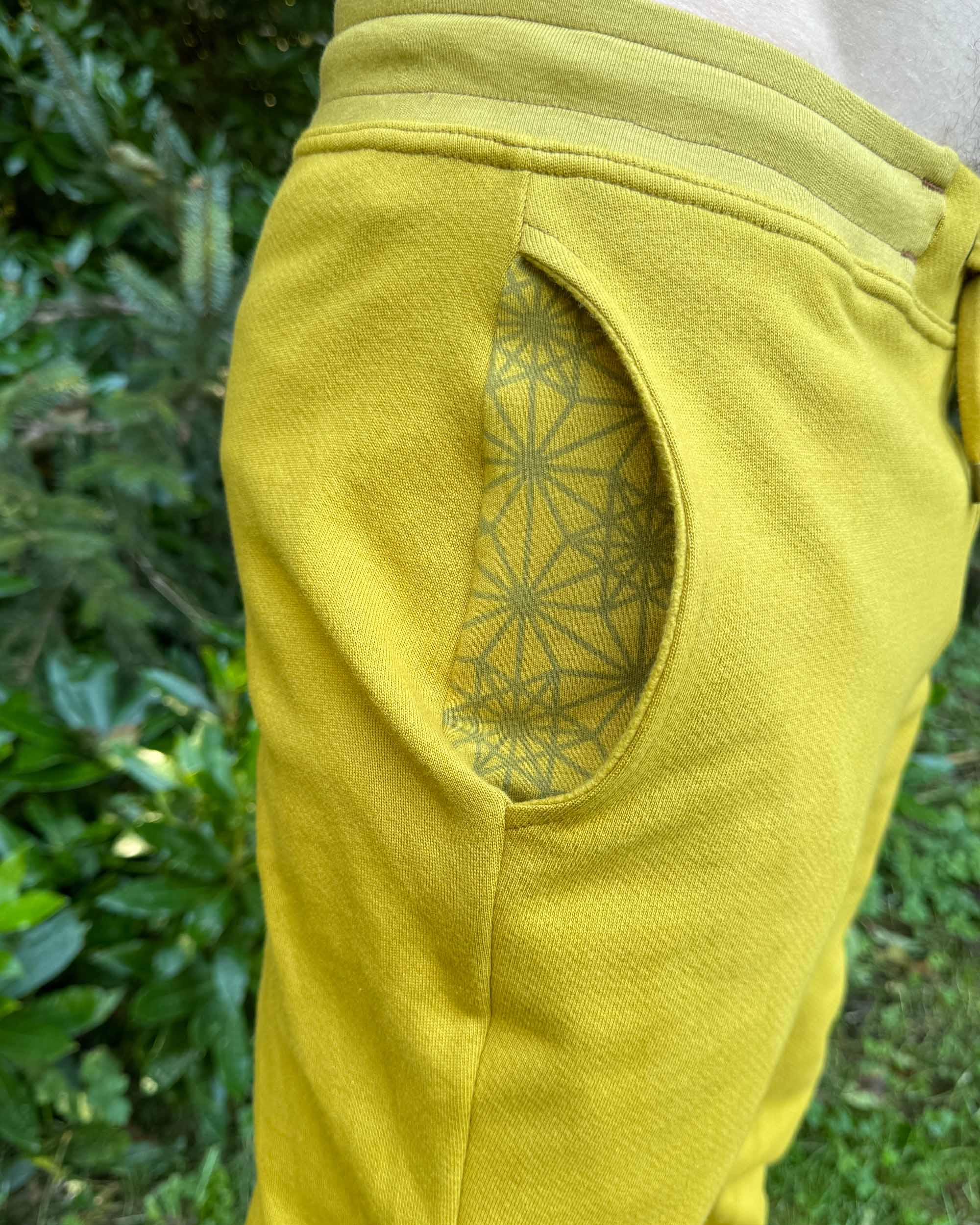 Organic cotton fleece joggers in yellow fabric, right side detail view of geometric printed pocket lining.